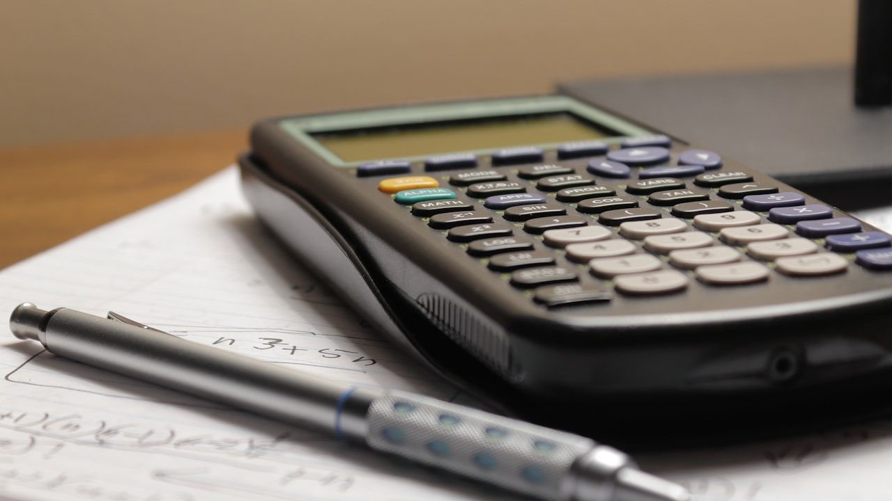 Scientific calculator resting on handwritten math notes with a pen, representing MDCAT aggregate merit calculation