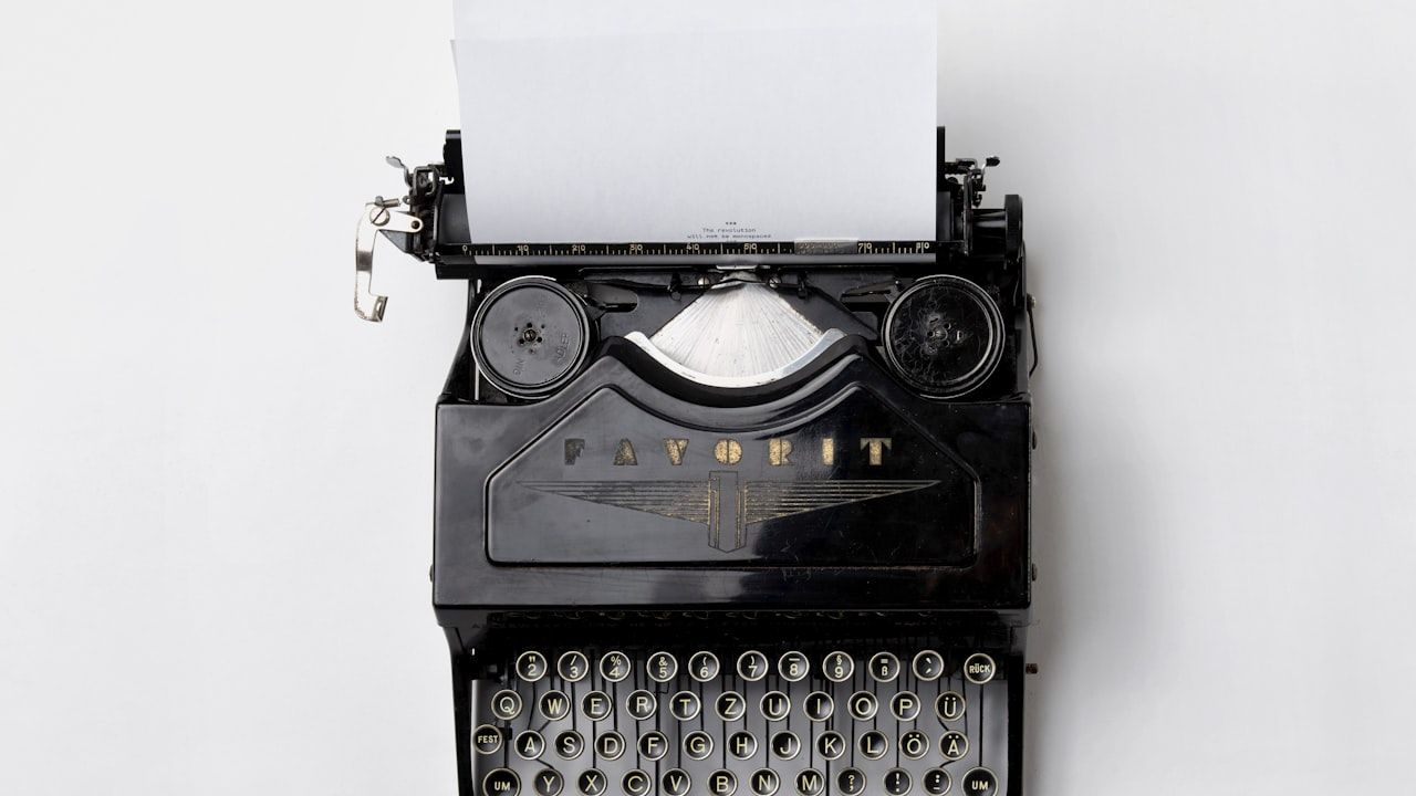 Black Favorit typewriter with a blank sheet of paper, viewed from above on a white background
