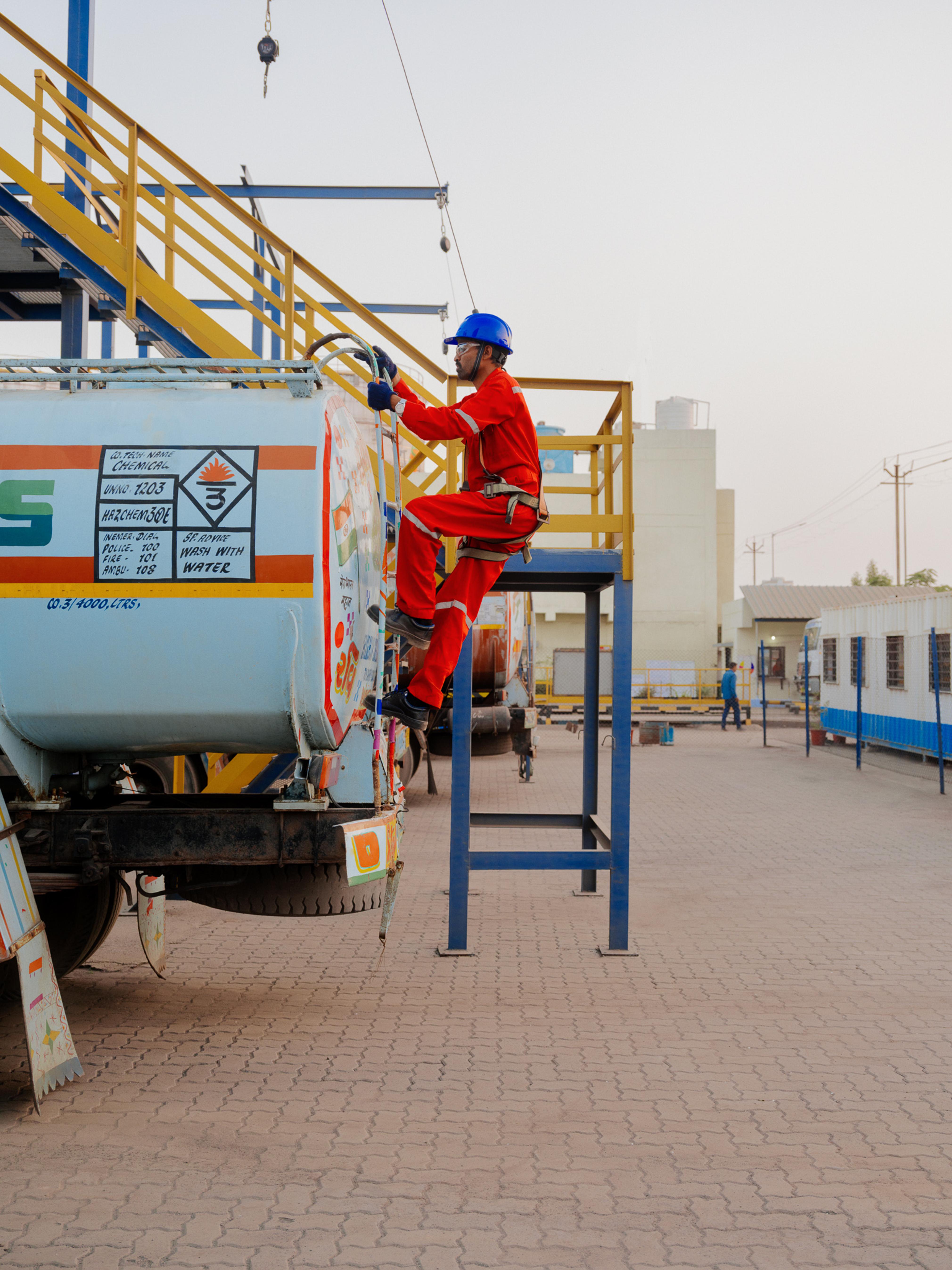 AVTL worker, attached to a safety harness, climbs down the back of a truck