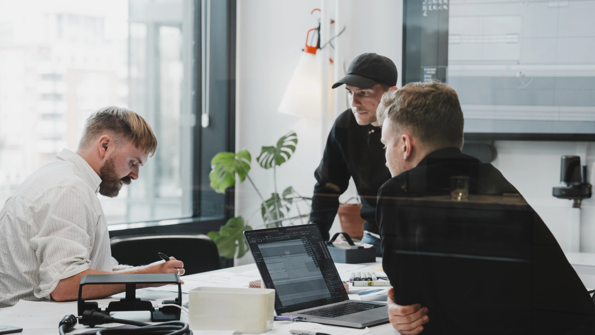 Three product designers seated at a table with laptops, actively planning and collaborating on their design project.