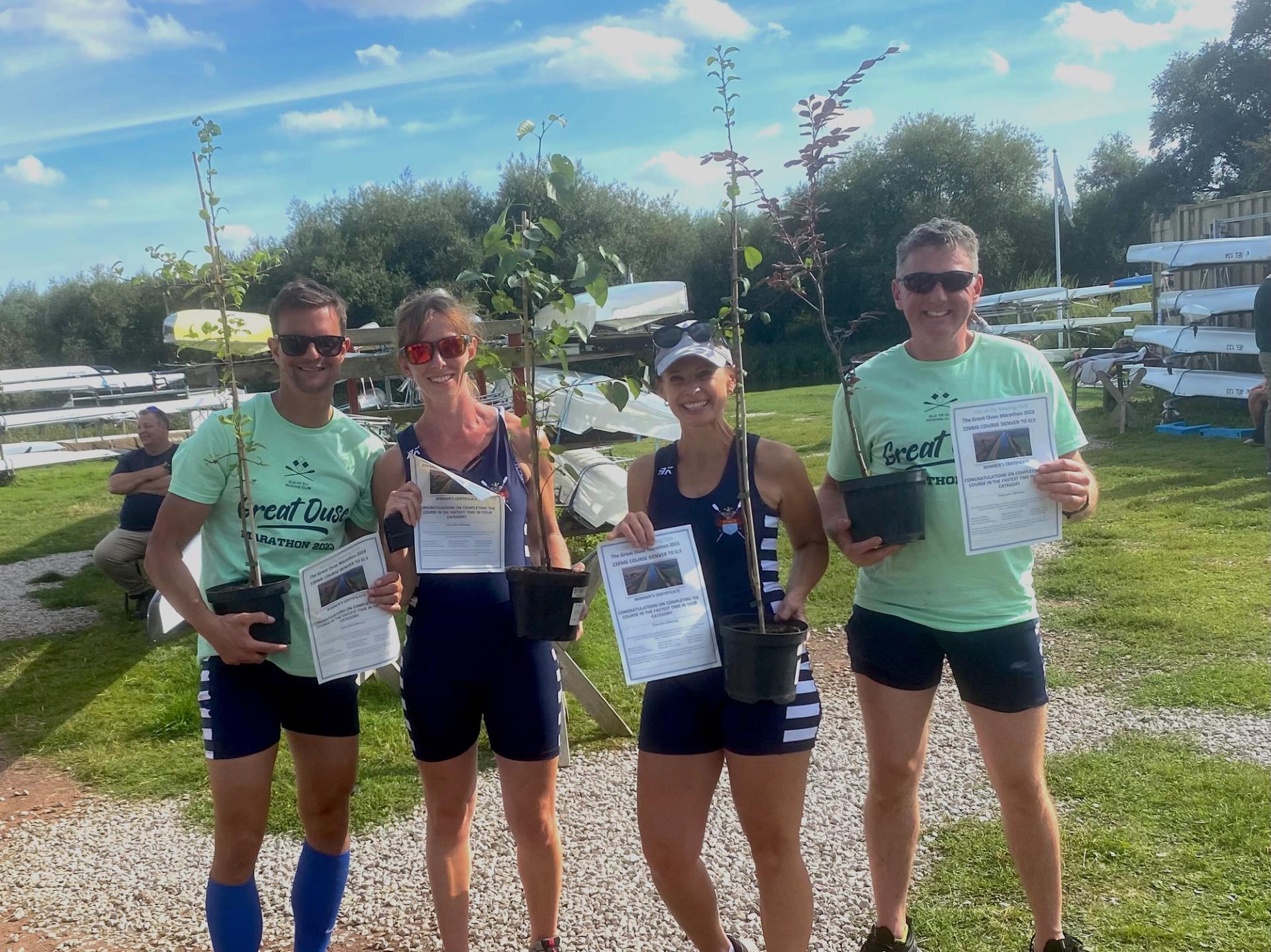 The members of two of the winning double pose for a photo after the race each holding a certificate and a small potted sapling. 