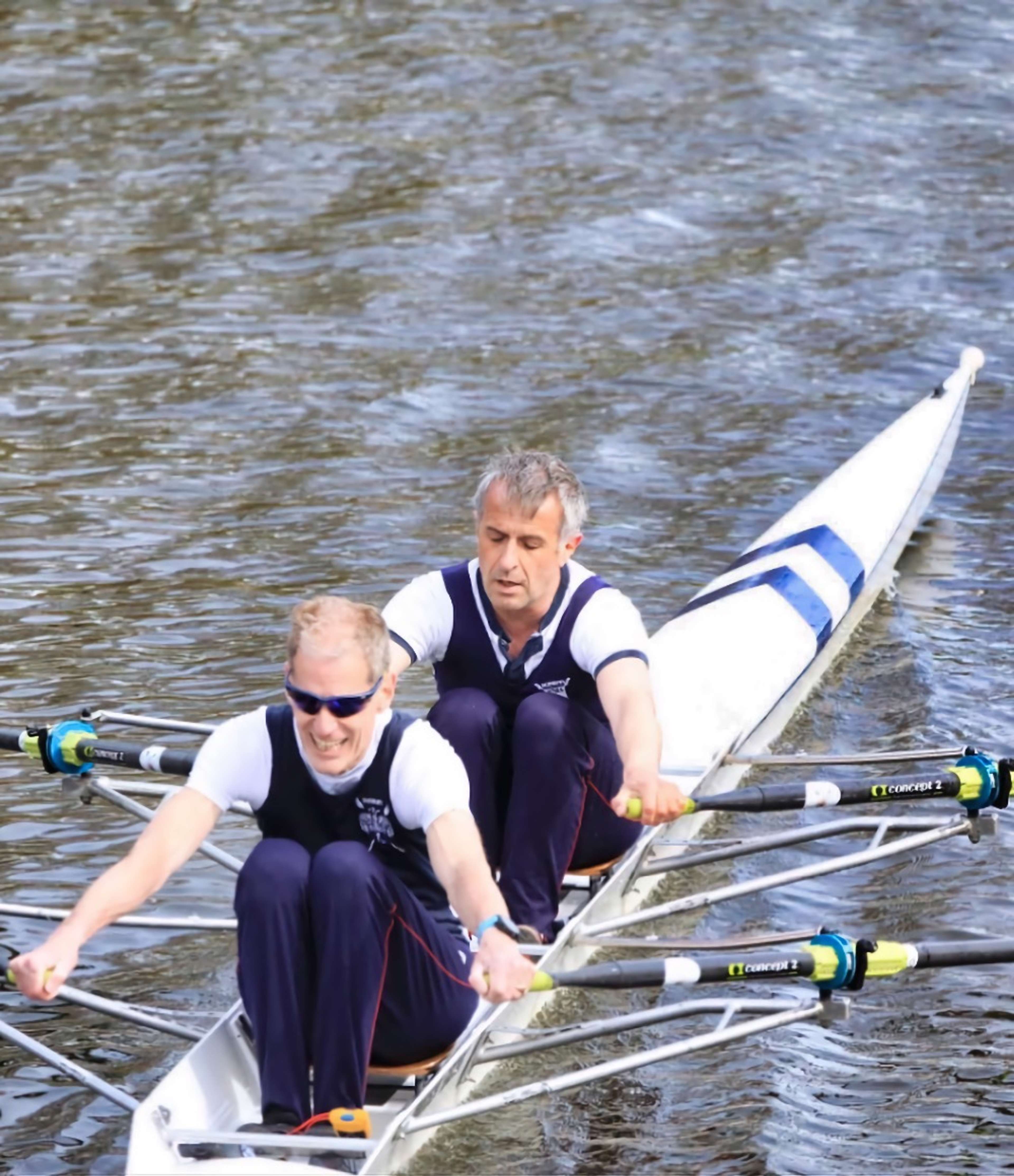 The Sudbury double passes beneath a bridge on the calm water in Bedford.