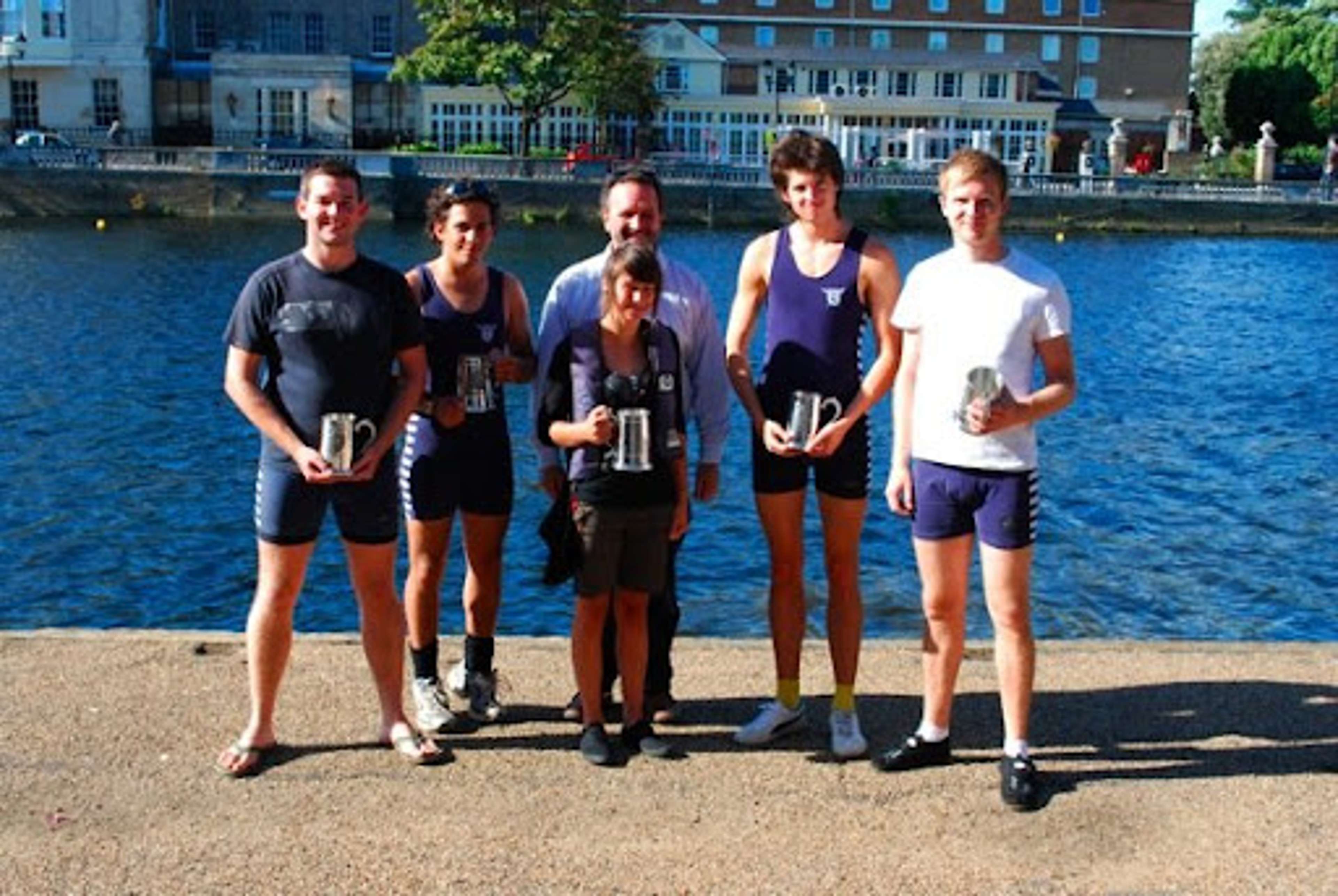 The successful coxed four, holding their pots by the river.