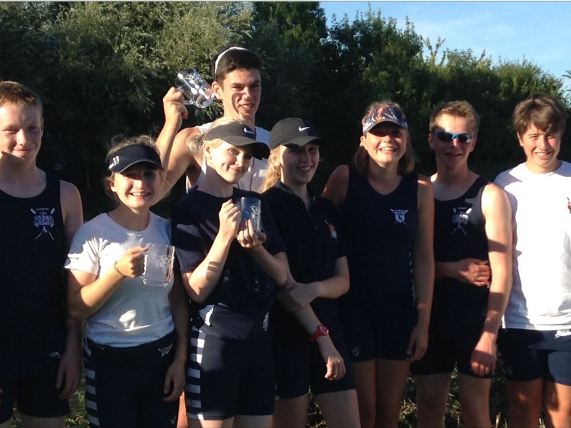 The attending junior members pose (three of whom have pots) for a photo in front of a riverside tree-line.