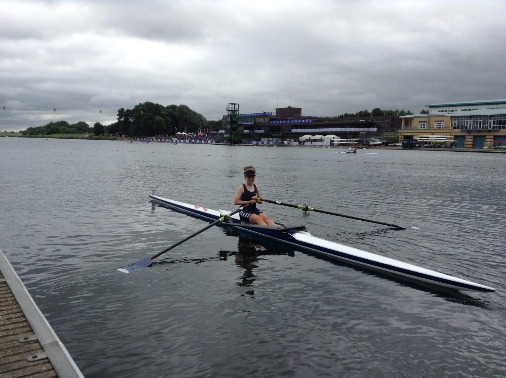 A junior single sculler at the landing stage in a large rowing lake. 