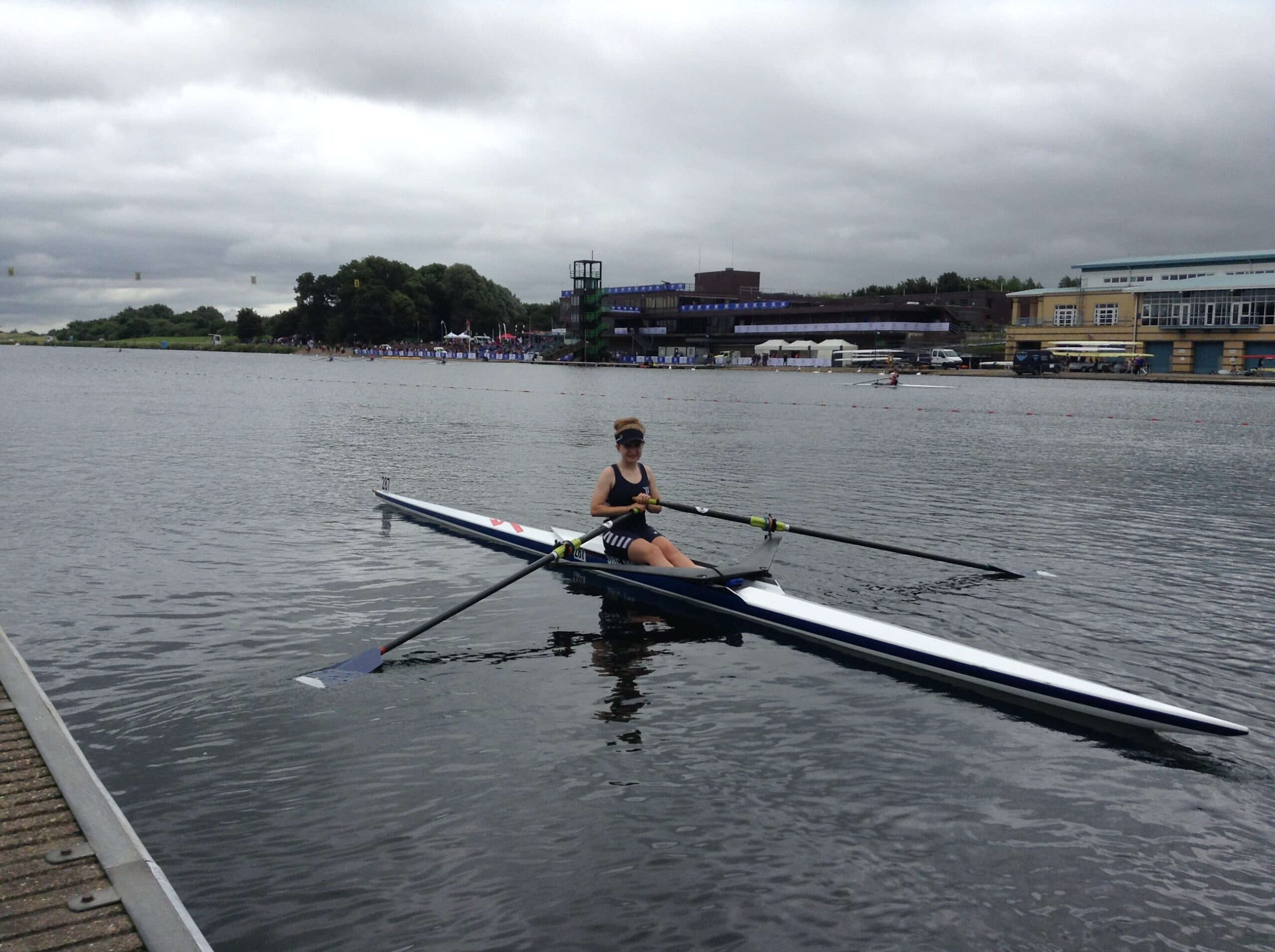 A junior single sculler at the landing stage in a large rowing lake.