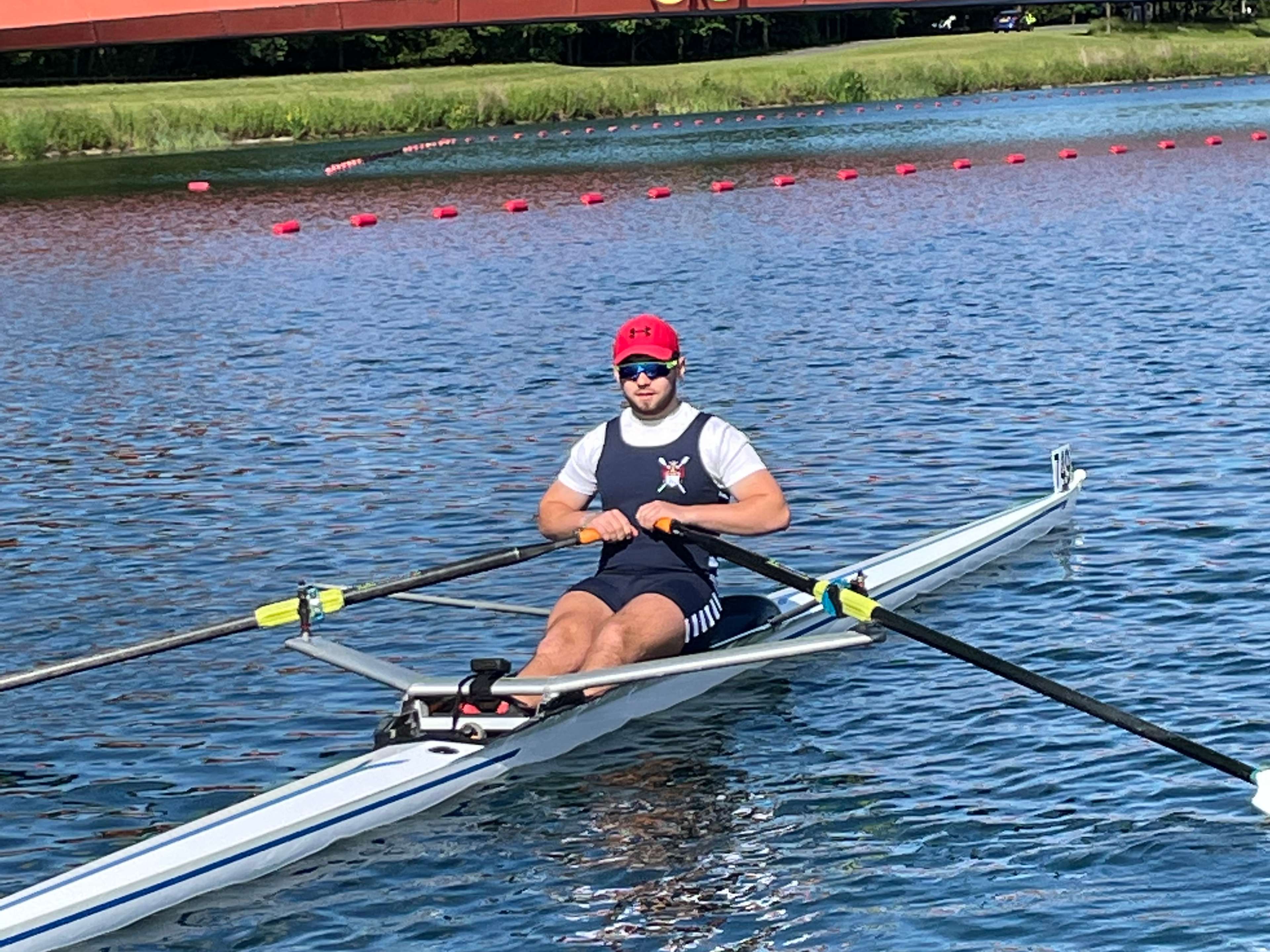 A male single sculler passing the olympic ring motif at the Dorney rowing lake.