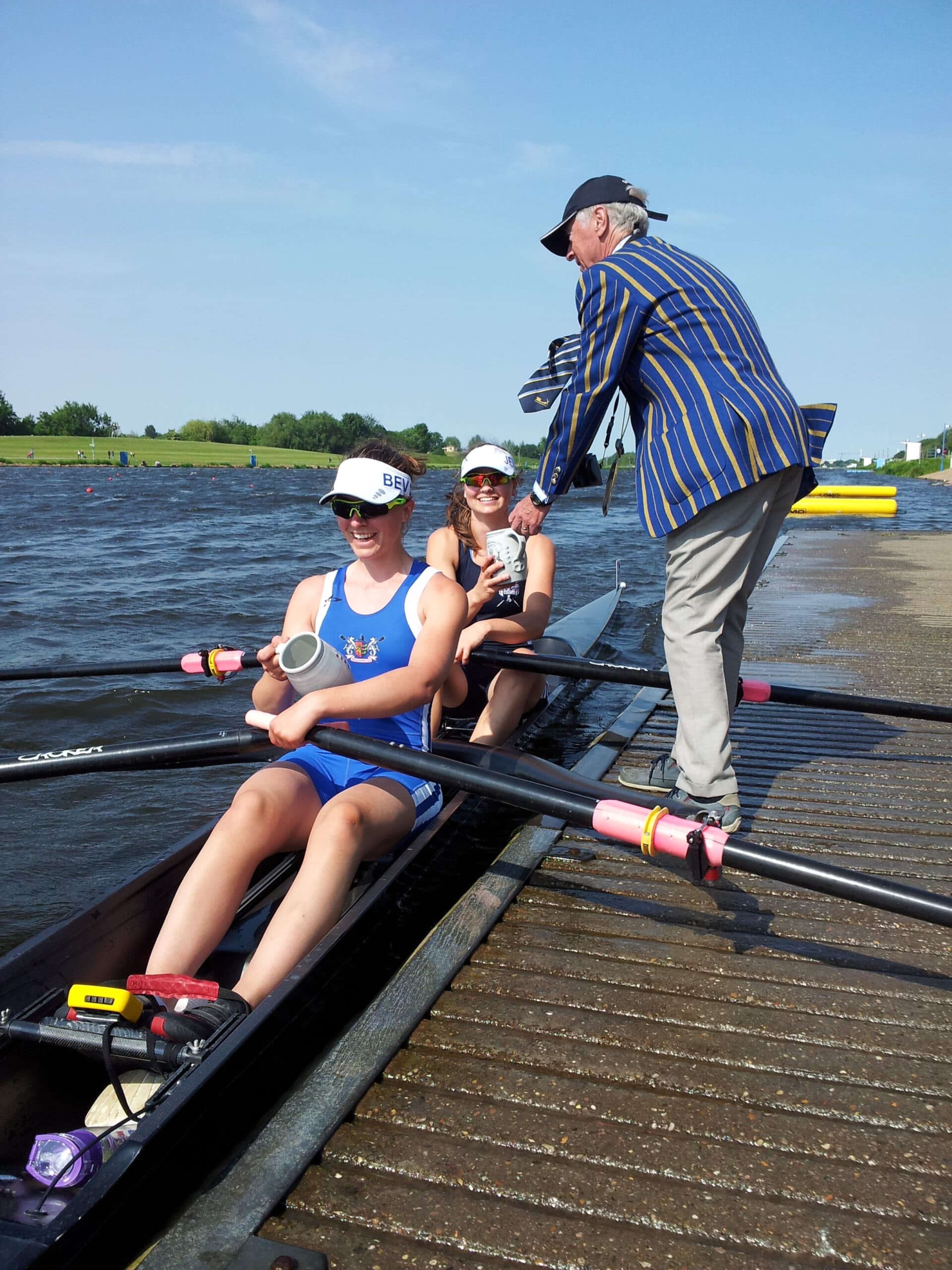 The scullers are handed their cups at the landing stage.