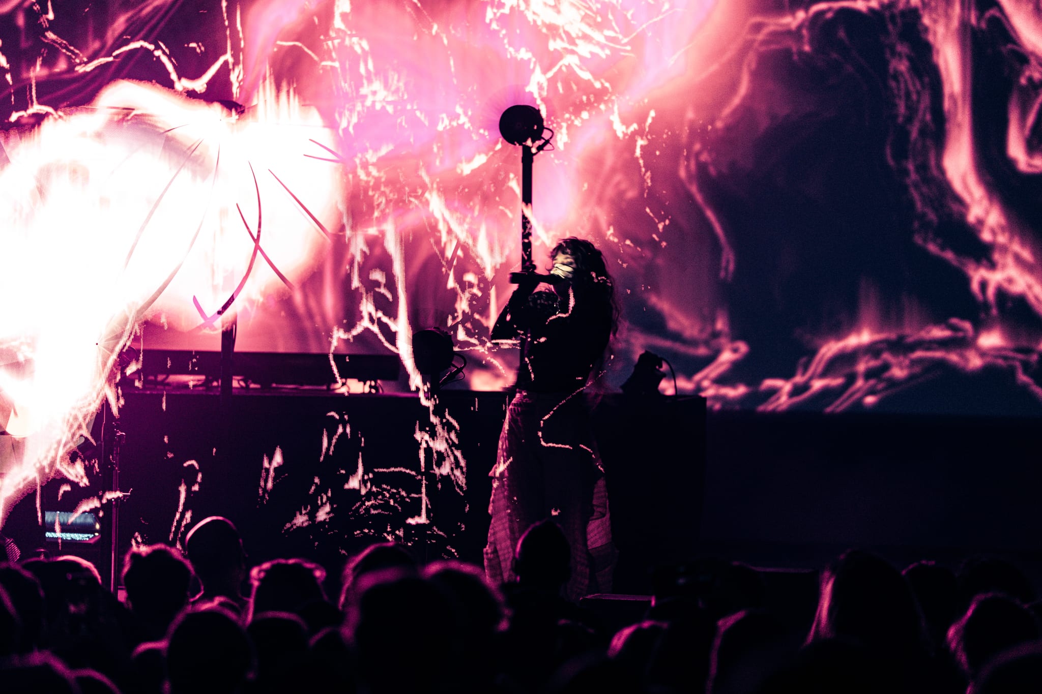 Purity Ring performing at Observatory North Park with fiery pink and magenta visuals projected behind them