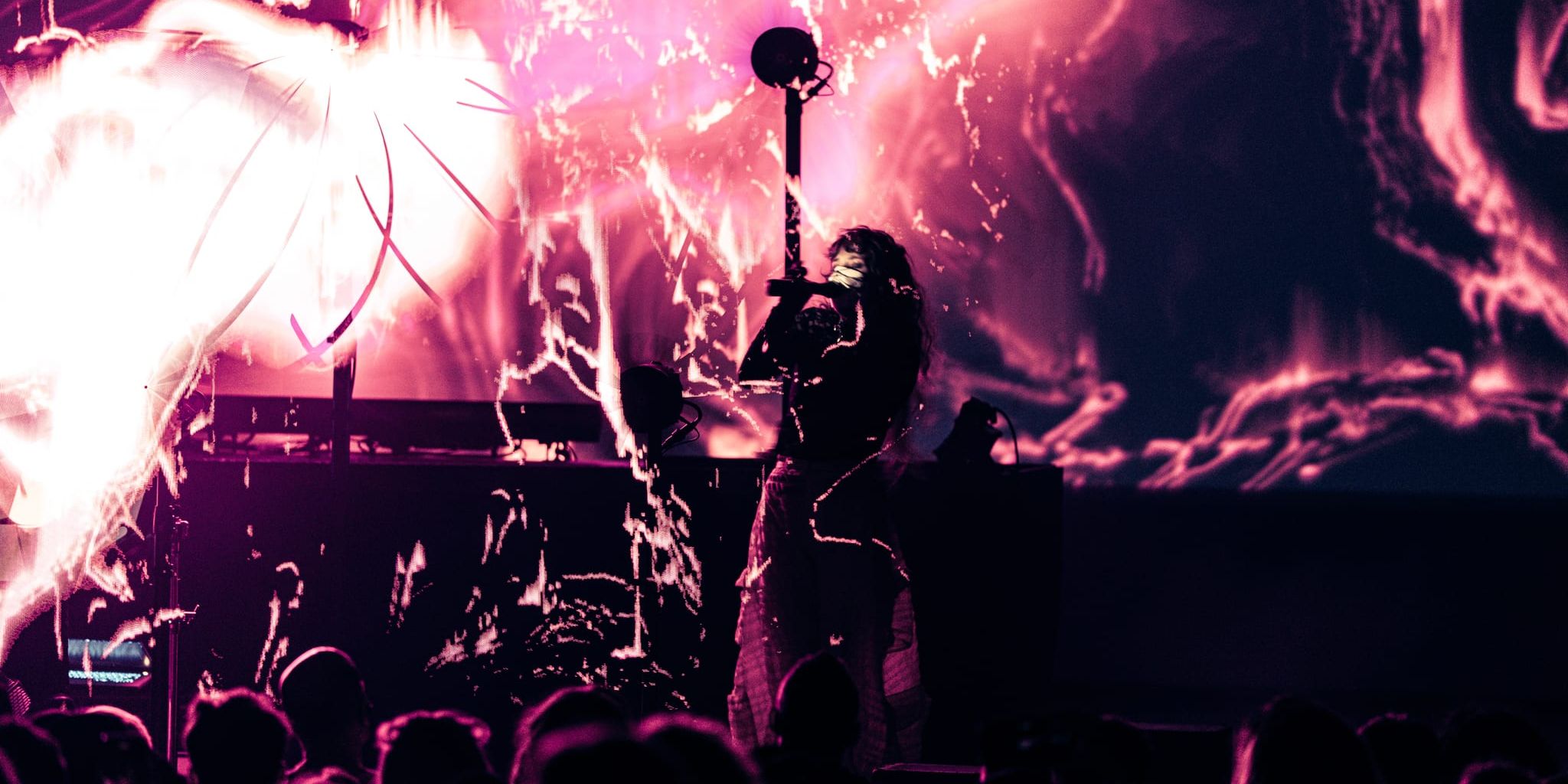 Purity Ring performing at Observatory North Park with fiery pink and magenta visuals projected behind them