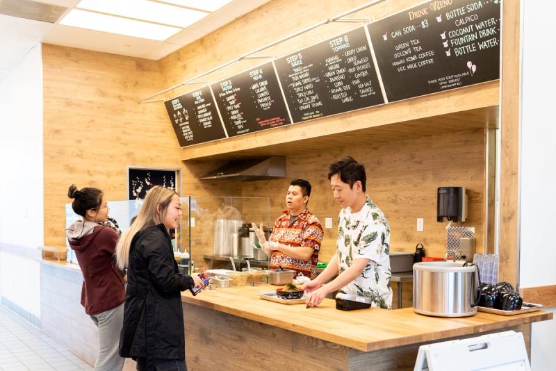 Business owner Justin Hwang take a customer's order for their custom poke bowl