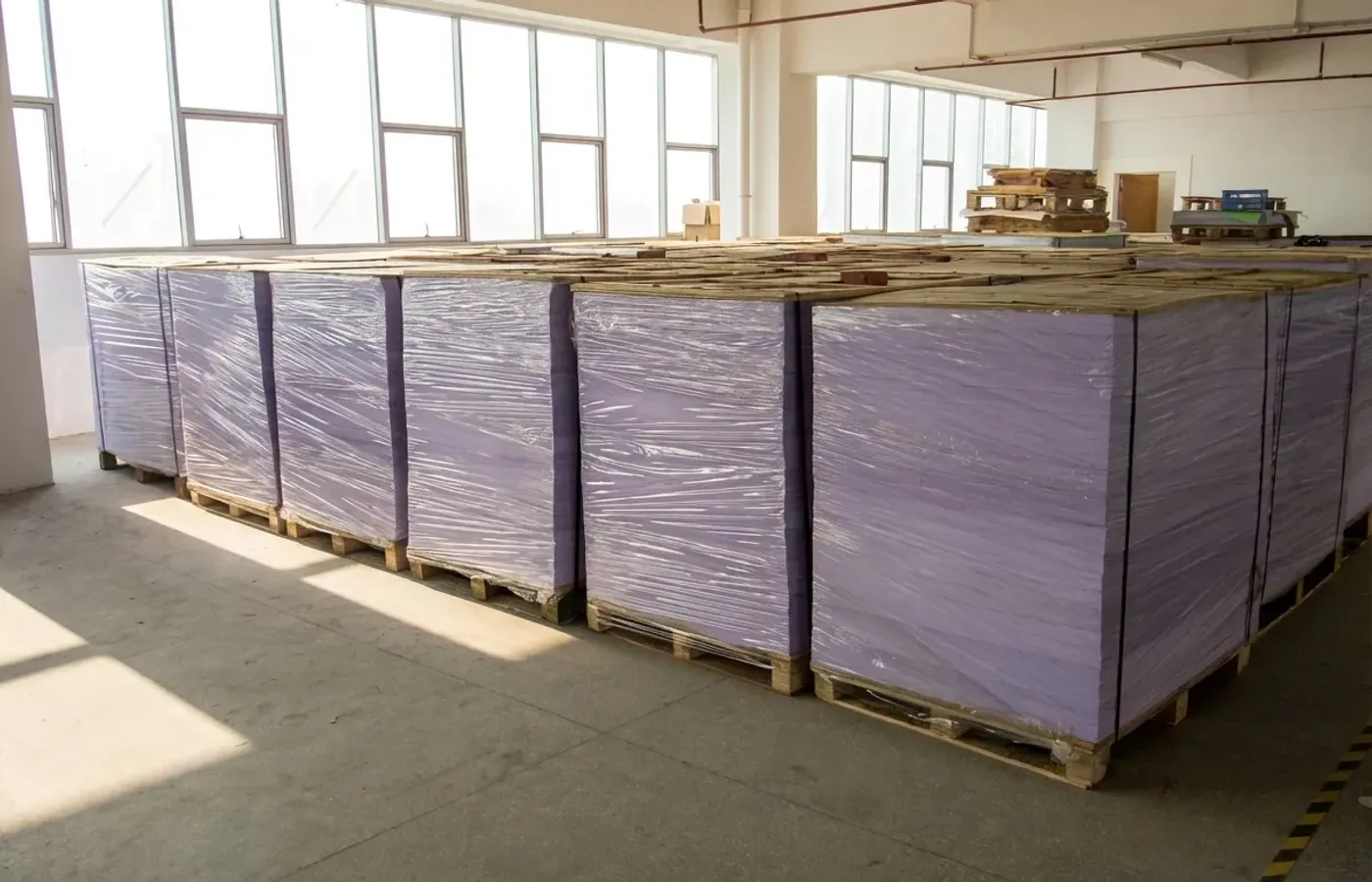 Large scale warehouse storing premium raw paper and film materials for sustainable B2B packaging production at Shinekin factory.