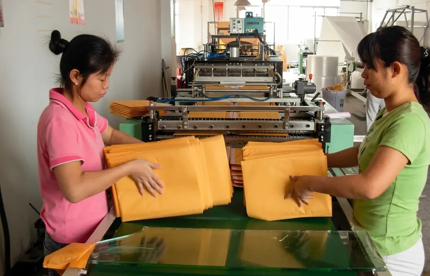Skilled factory workers operating high-speed kraft envelope production machinery at Shinekin Packing facility in China.