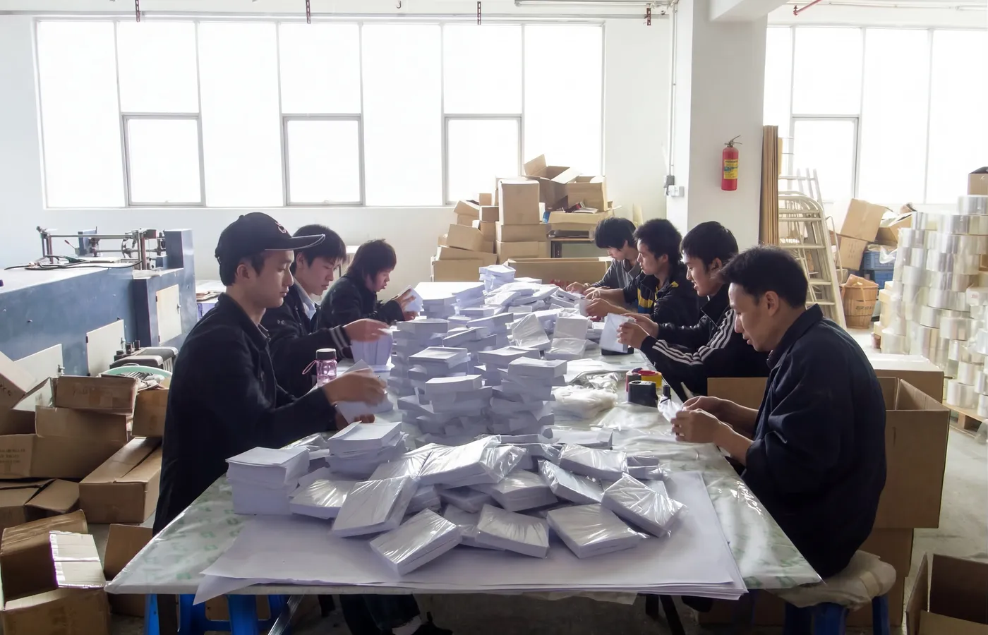 Skilled factory workers operating high-speed kraft envelope production machinery at Shinekin Packing facility in China.