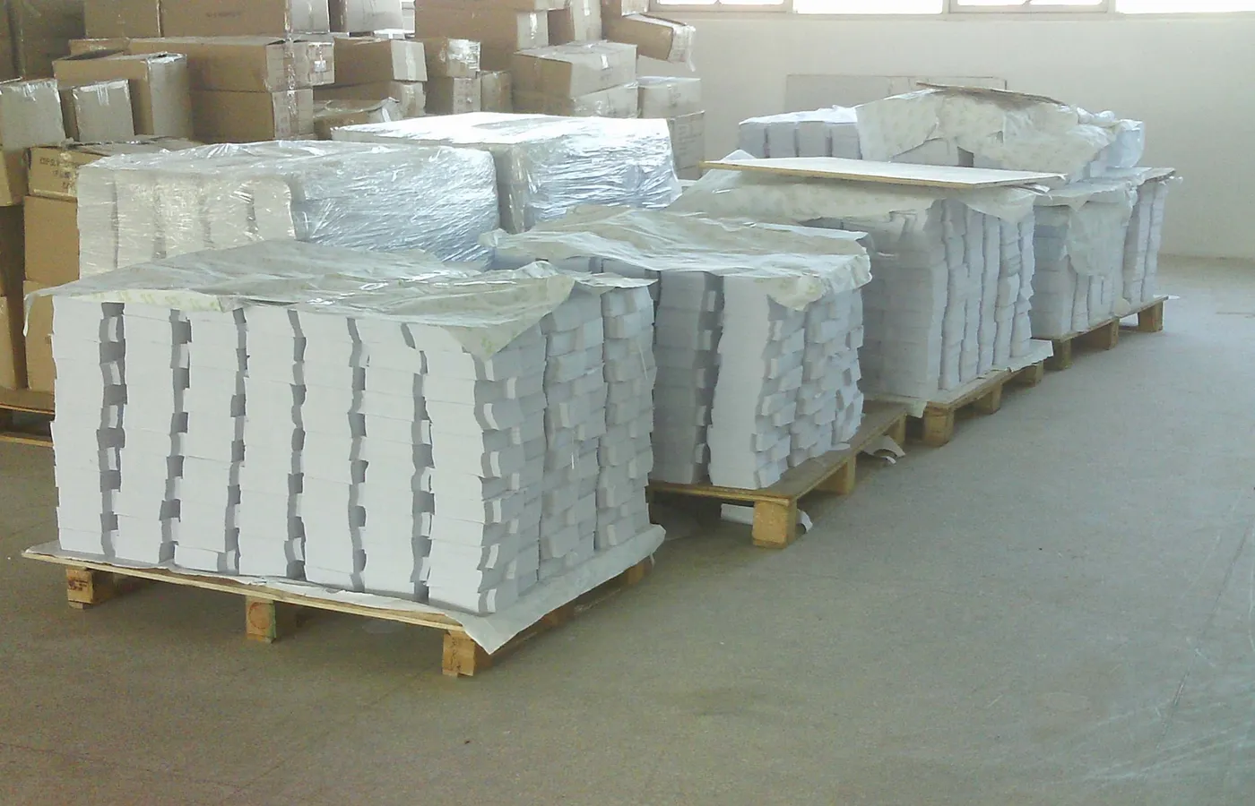 Large scale warehouse storing premium raw paper and film materials for sustainable B2B packaging production at Shinekin factory.