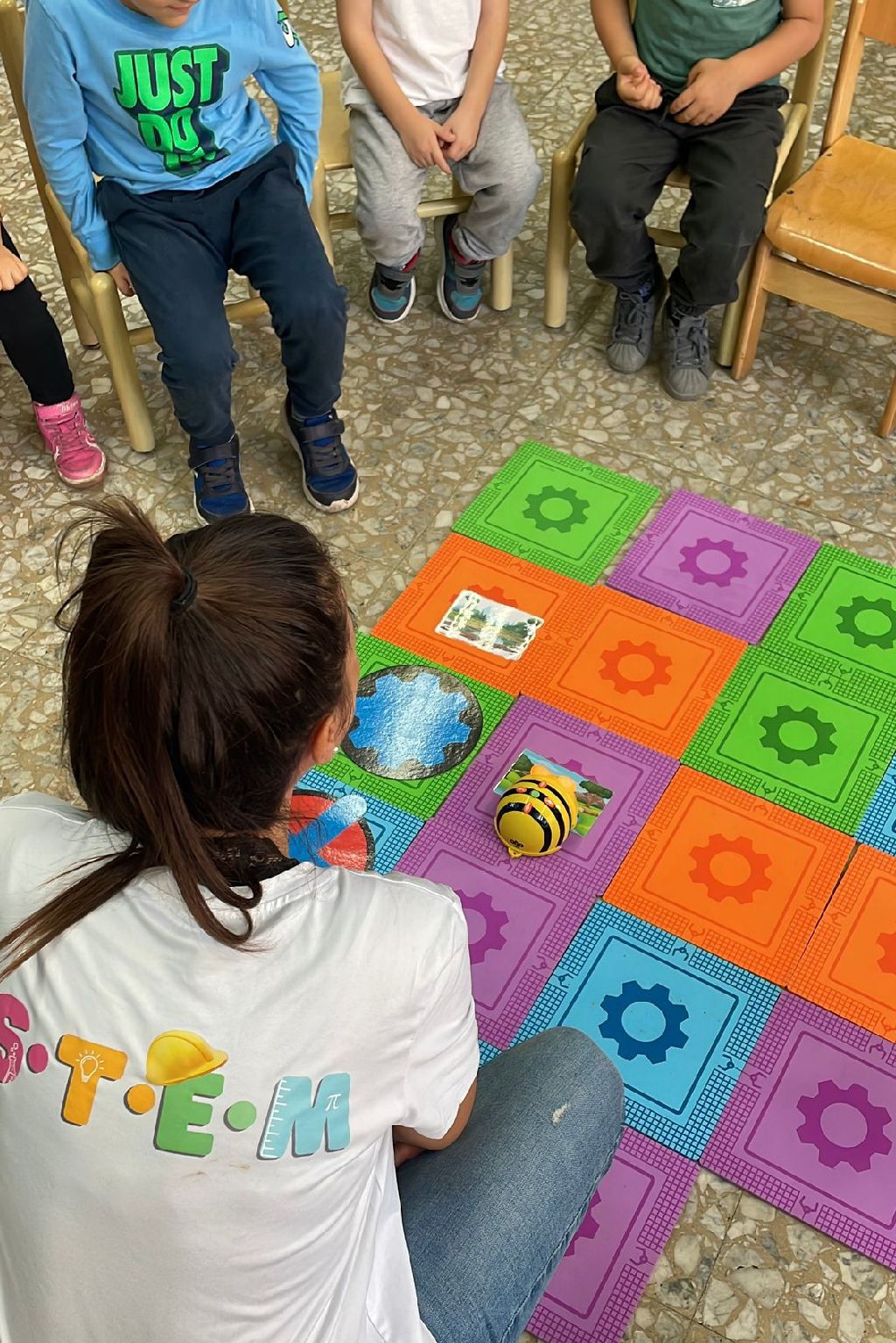 Bambini seduti sul tappeto a quadri colorati durante un laboratorio STEM