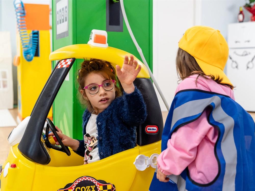 Due bambini giocano con una macchinina a pedali in ludoteca