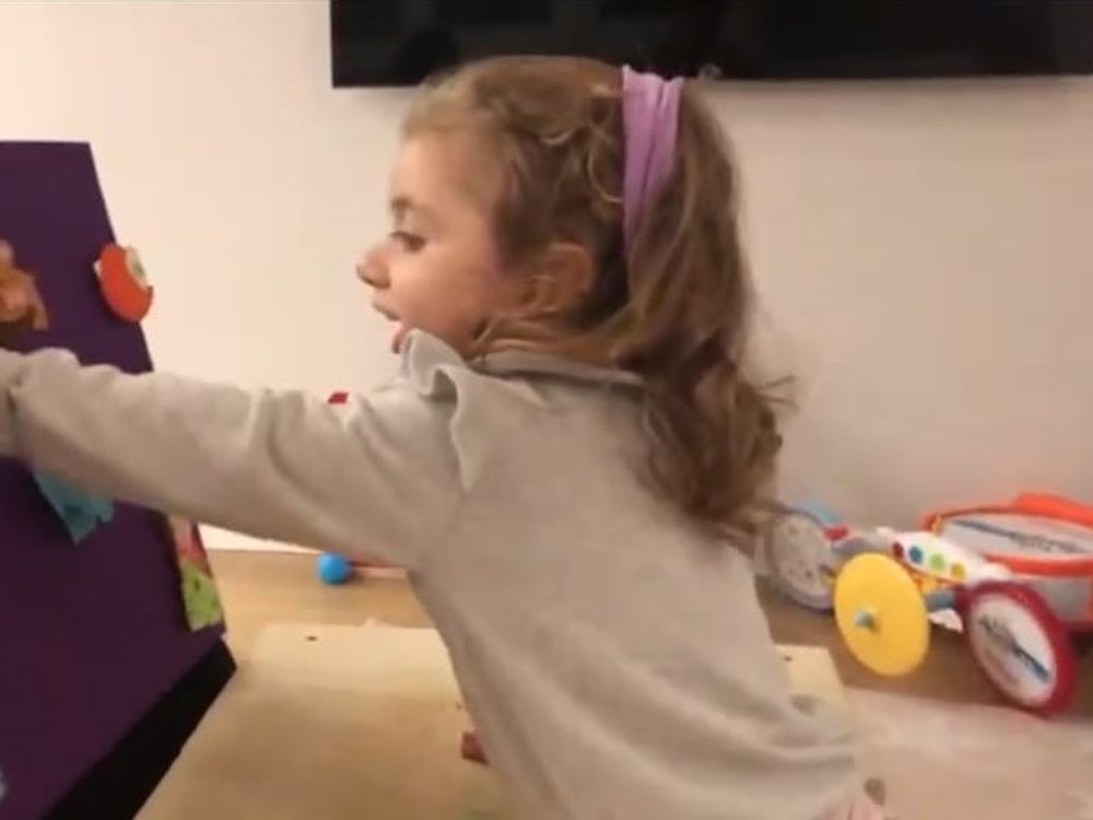Una bambina attacca sagome di animali su un pannello di feltro