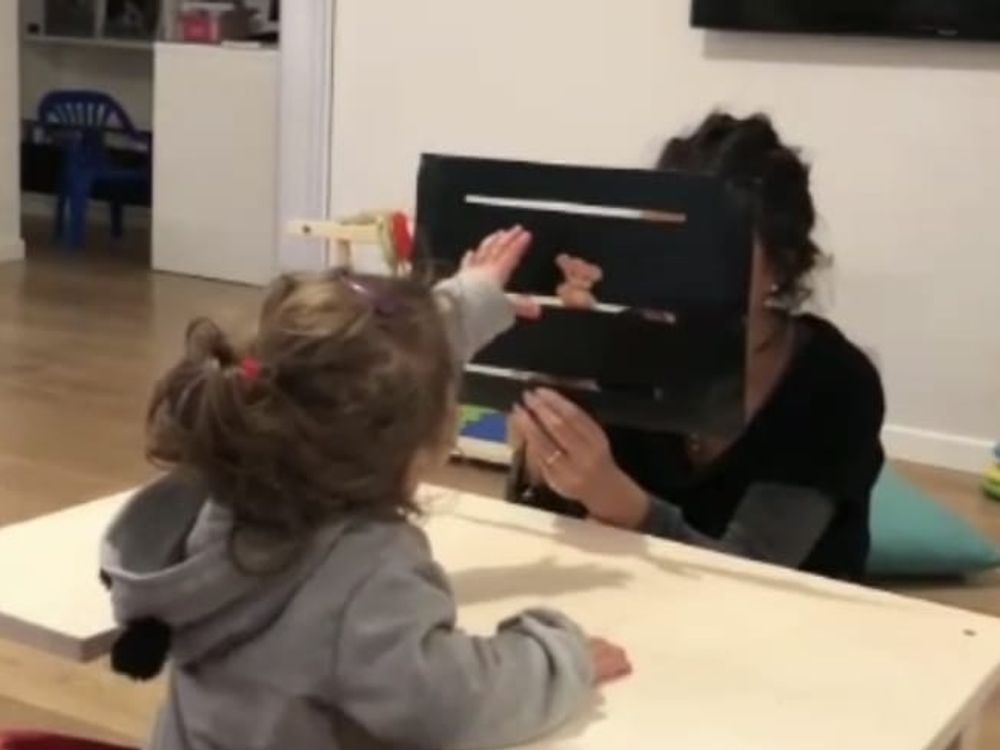 Una bambina gioca a un tavolino con un’educatrice
