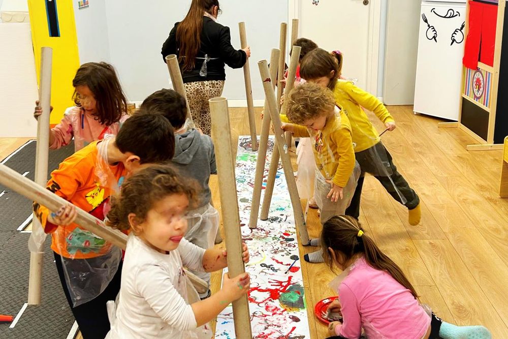 Bambini che dipingono su un lungo rotolo di carta