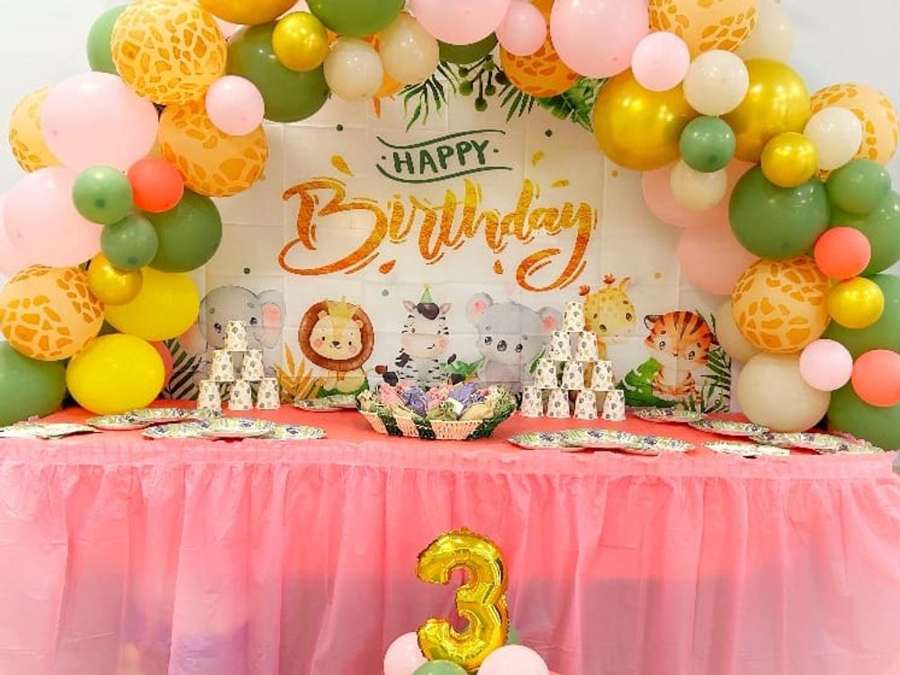Allestimento a tema animali della giungla: arco di palloncini, sfondo e tavolo con la gonna rosa