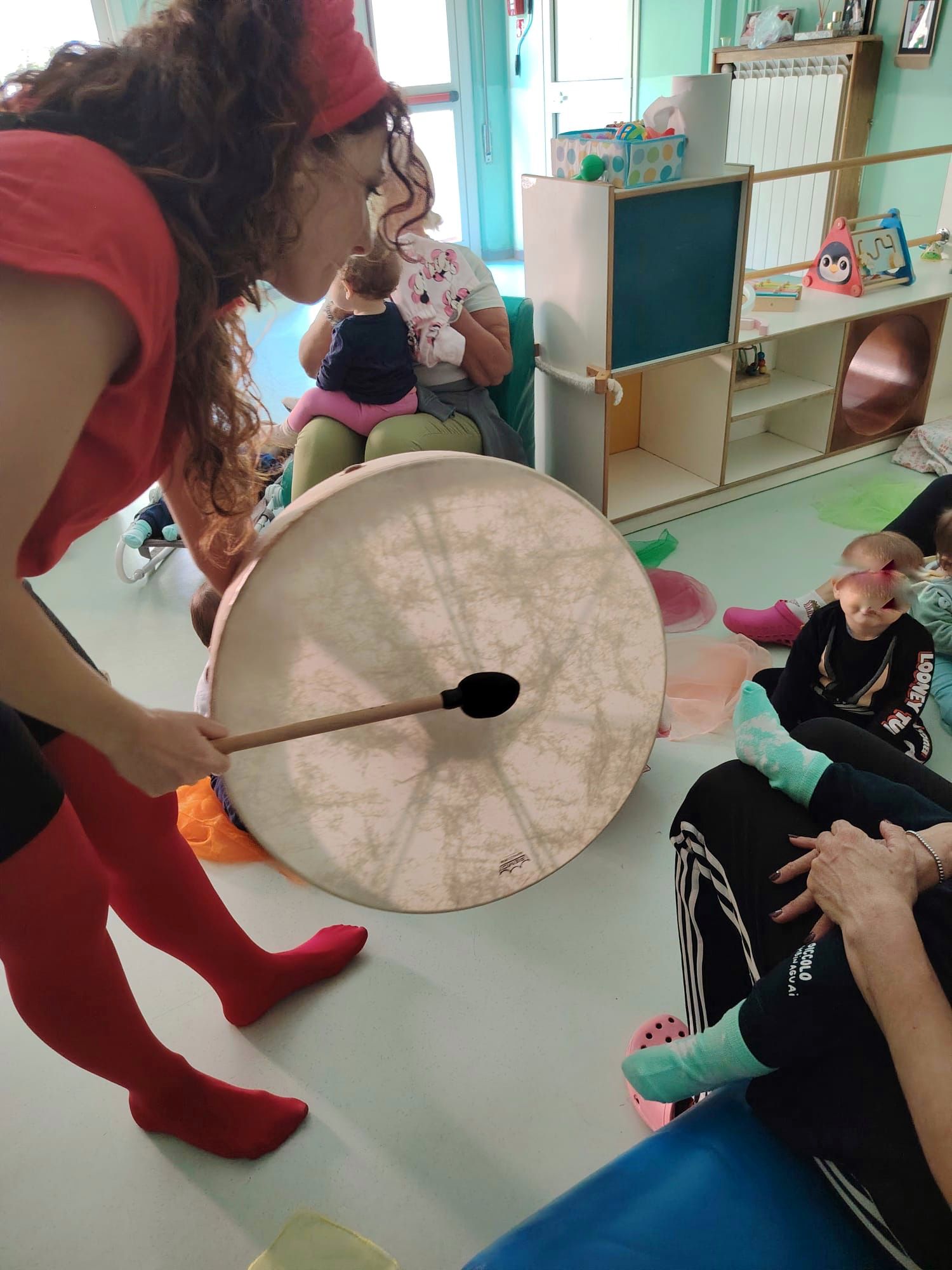 Una musicista suona un grande tamburo davanti ai bambini