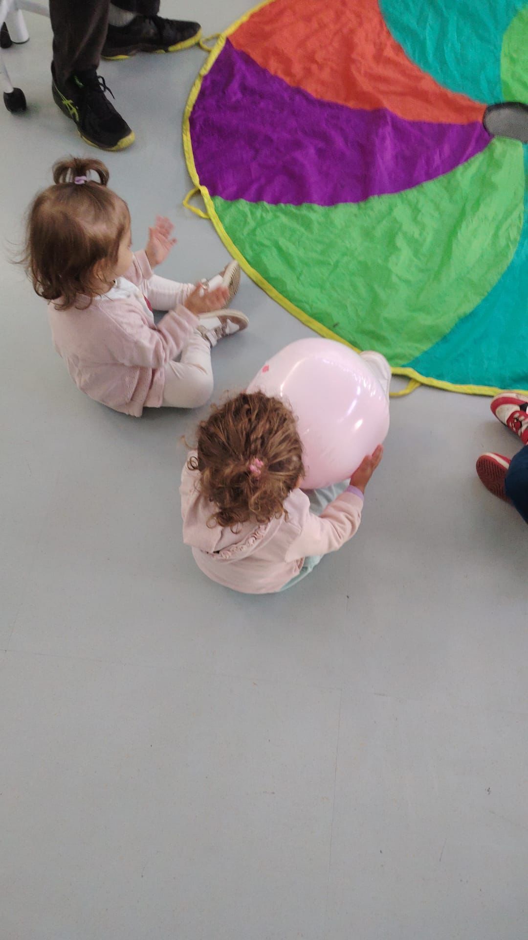 Due bambine piccole accanto a un paracadute colorato