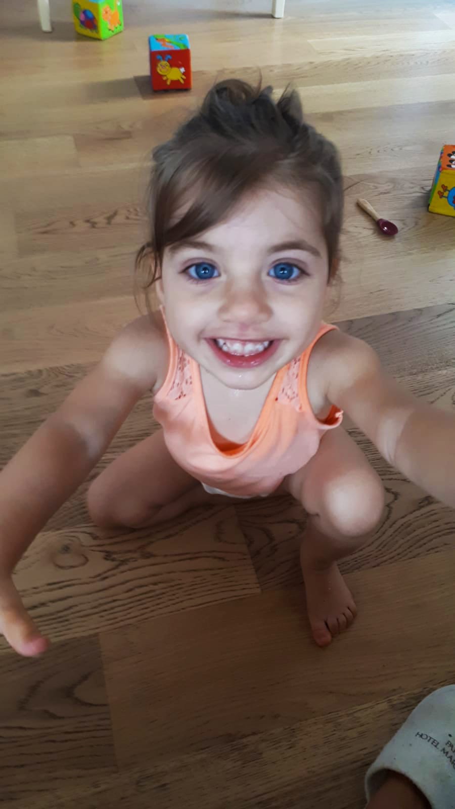 Una bambina seduta sul pavimento, sorridente