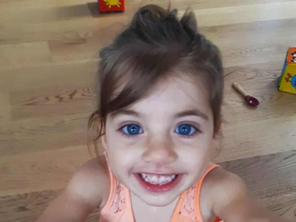 Una bambina seduta sul pavimento, sorridente