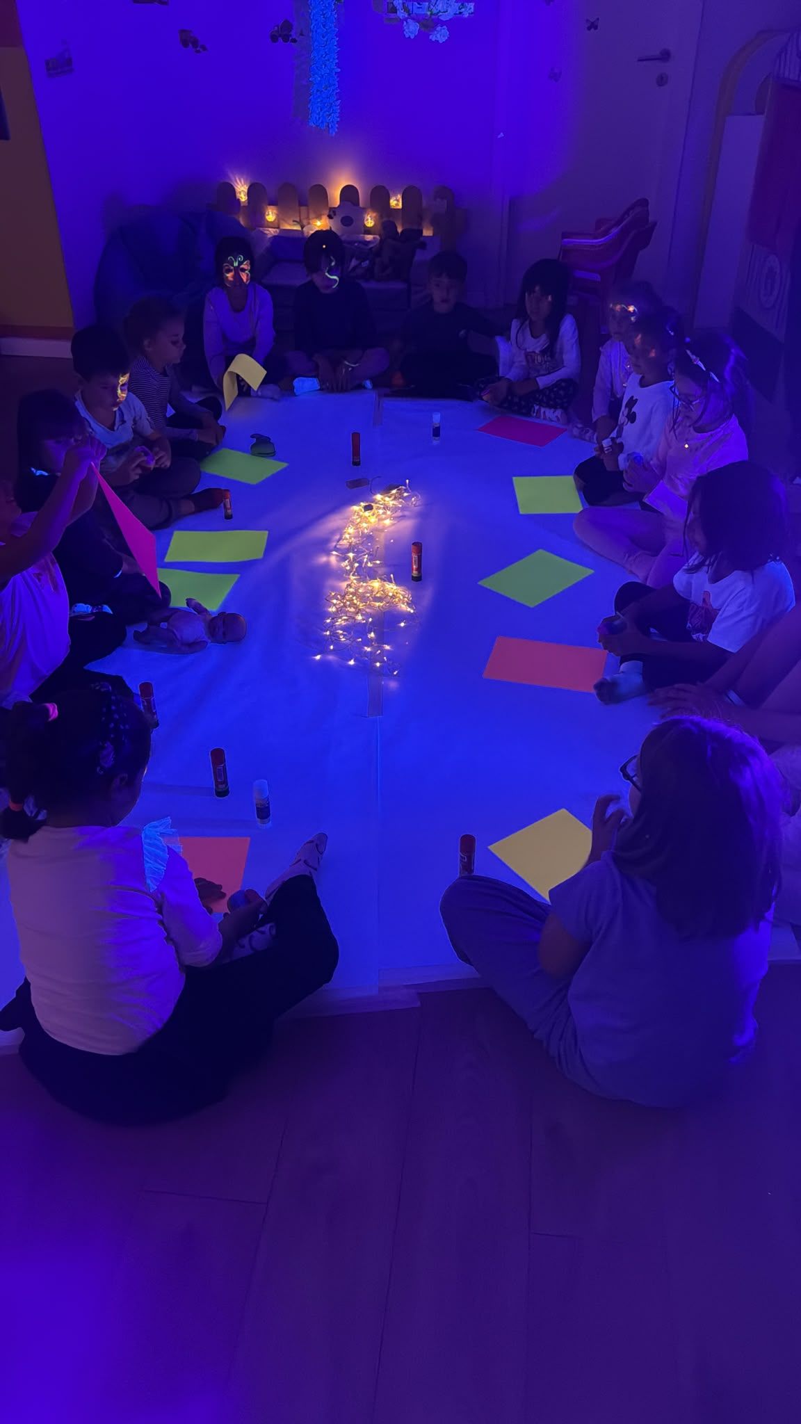 Bambini seduti in cerchio al buio, intorno alle luci