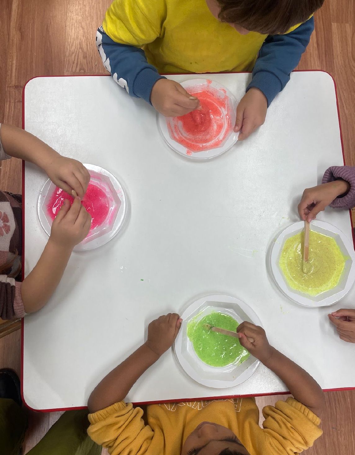 Bambini che mescolano lo slime nei piatti, visti dall’alto