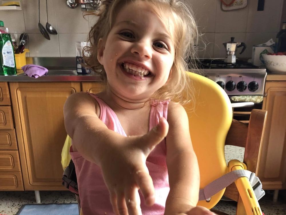 Una bambina in cucina con le mani in pasta