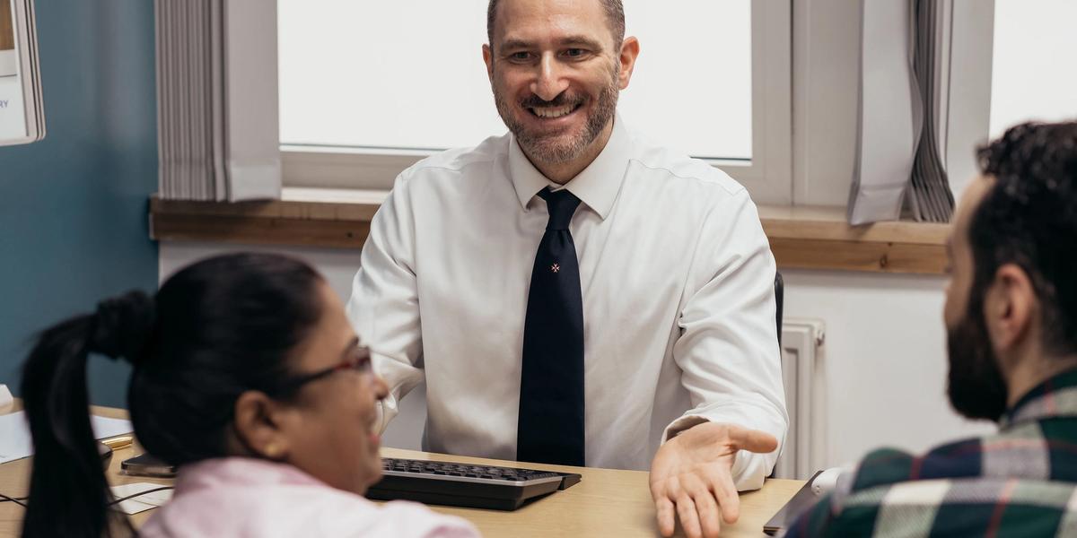 A couple is having their first fertility consultation in clinic. The clinician is welcoming and smiling.