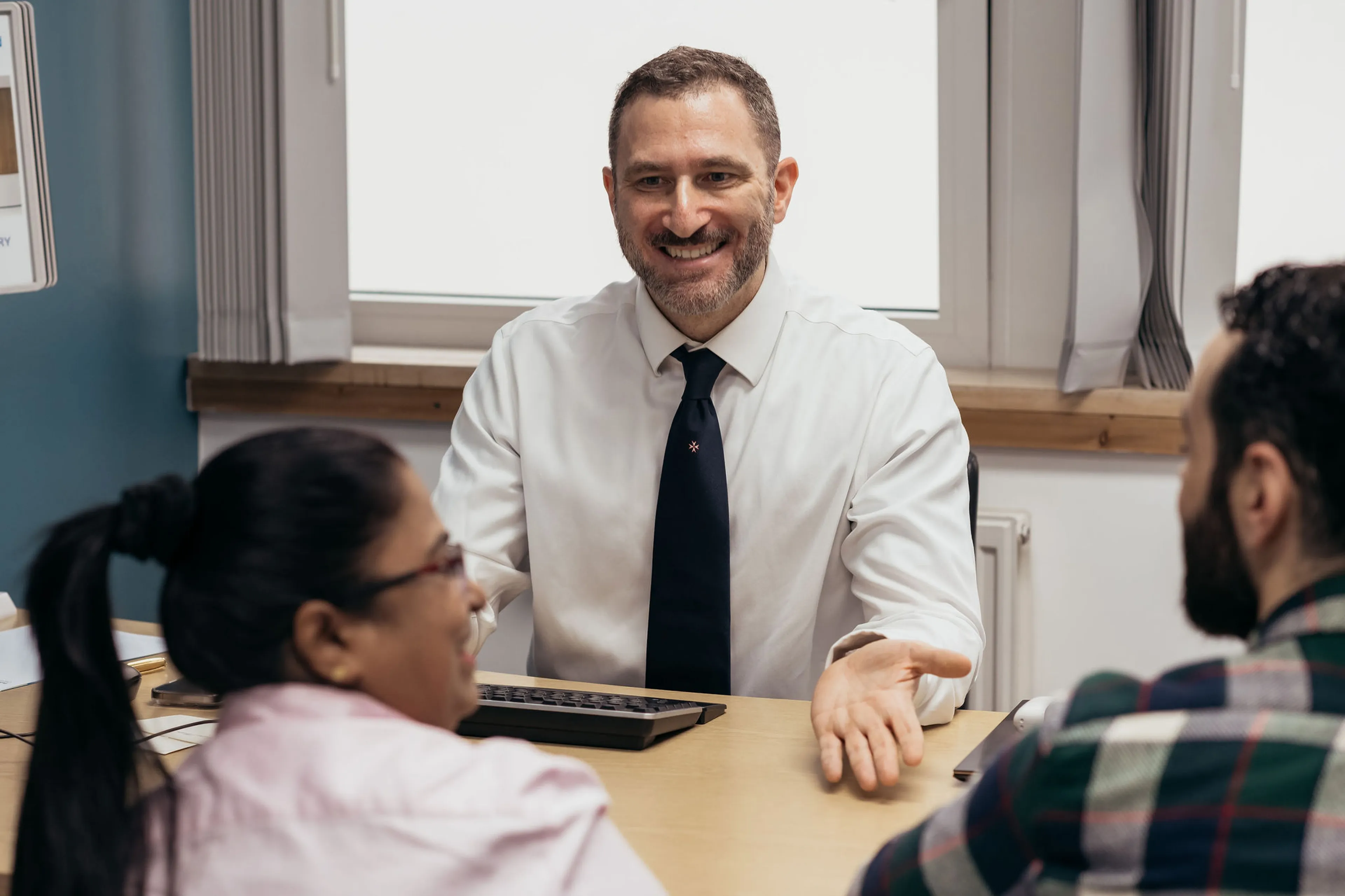 A couple is having their first fertility consultation in clinic. The clinician is welcoming and smiling.