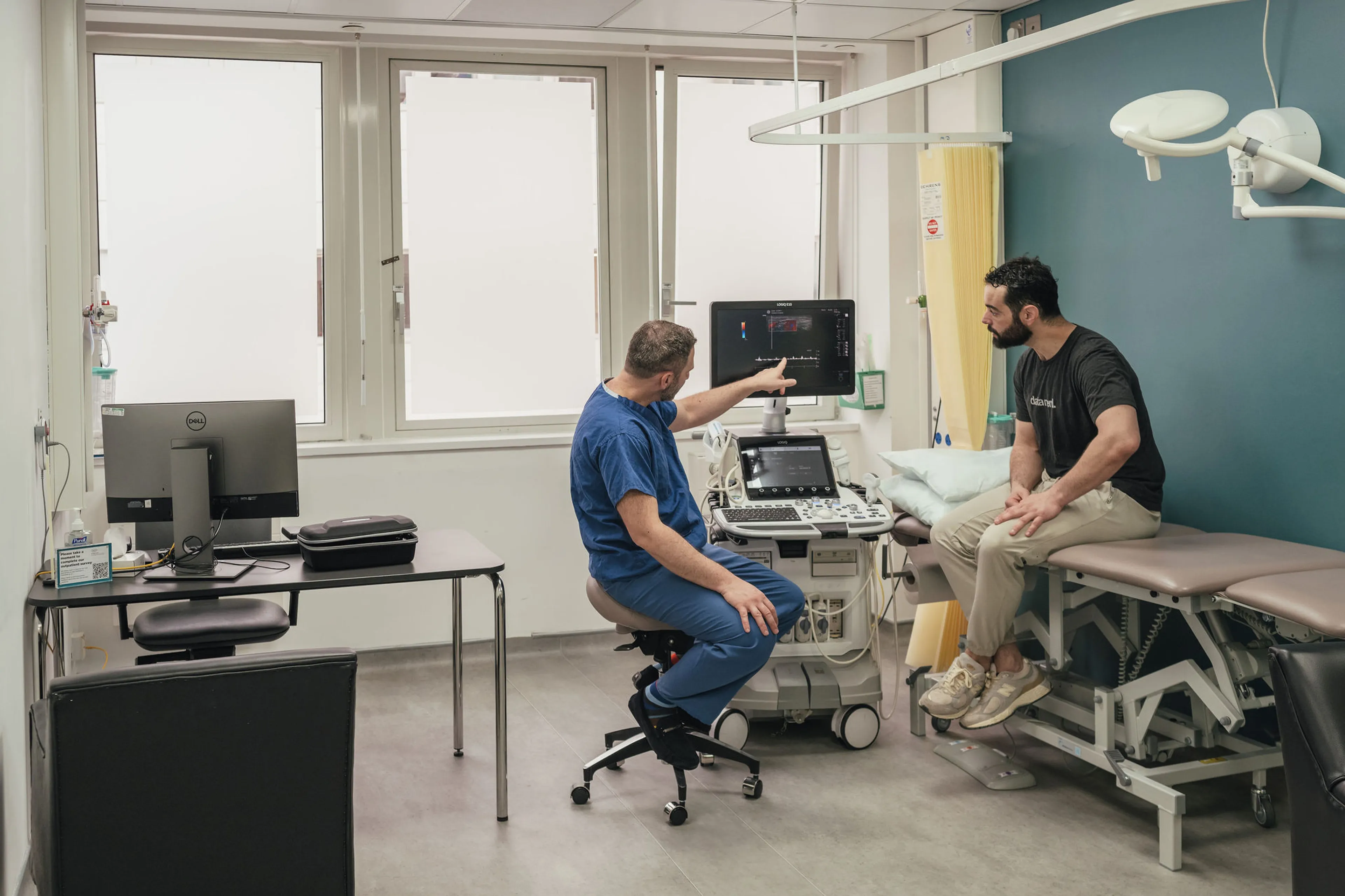 Consultant urologist explaining penile Doppler ultrasound results to a patient during an outpatient andrology assessment in London.