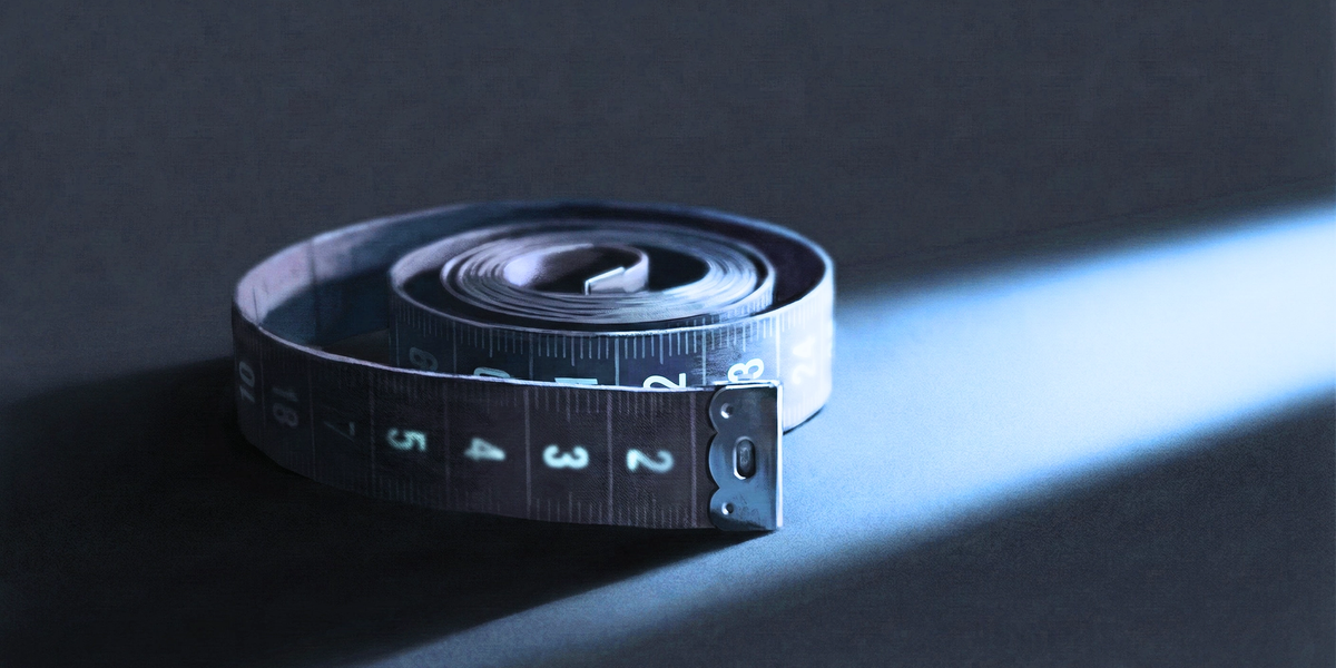 A coiled measuring tape in dramatic low lighting, symbolising the obsessive self-measurement cycle in penile dysmorphic disorder