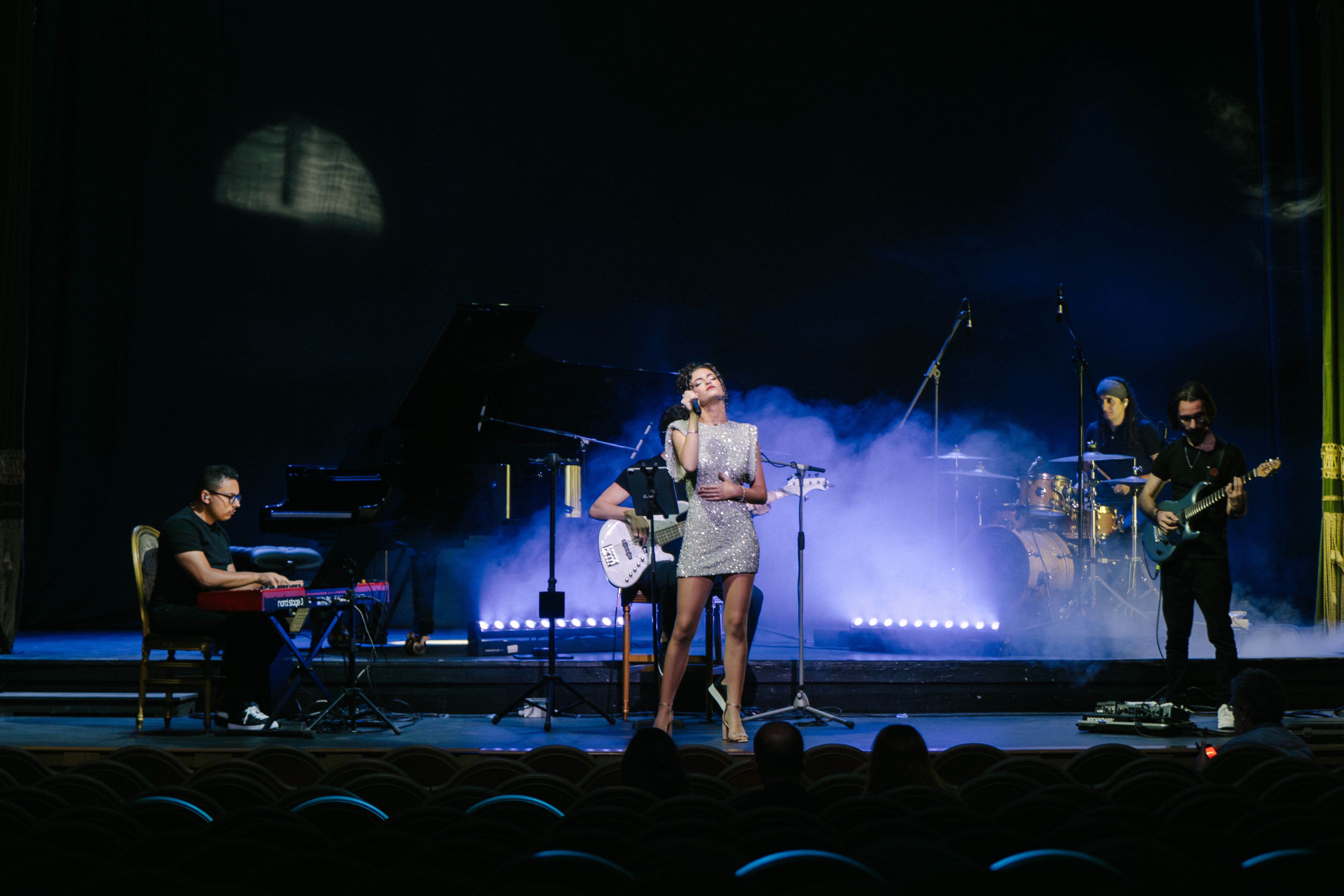 singer in silver dress with band
