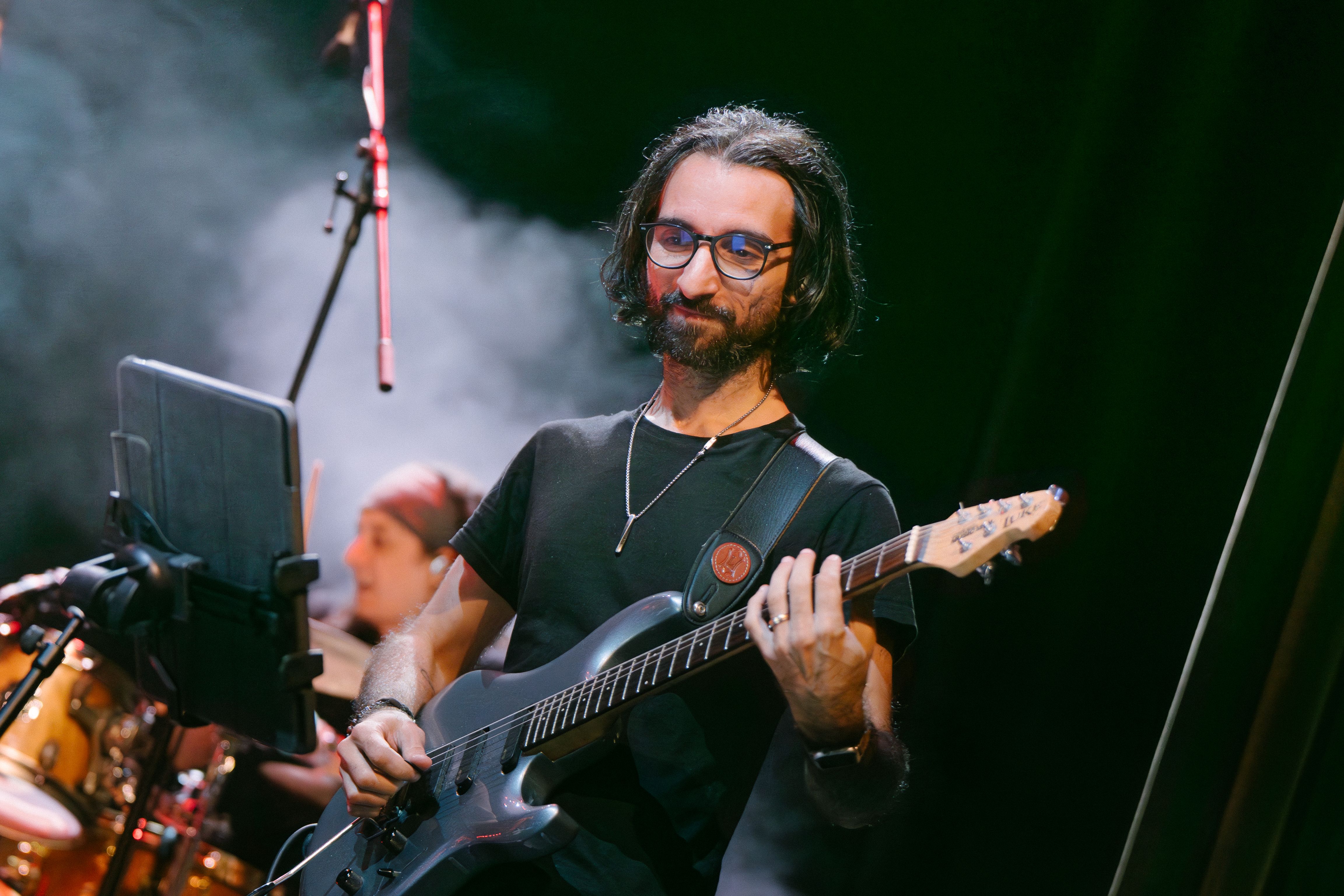 guitarist at the forefront and drummer with smoke around him in the background