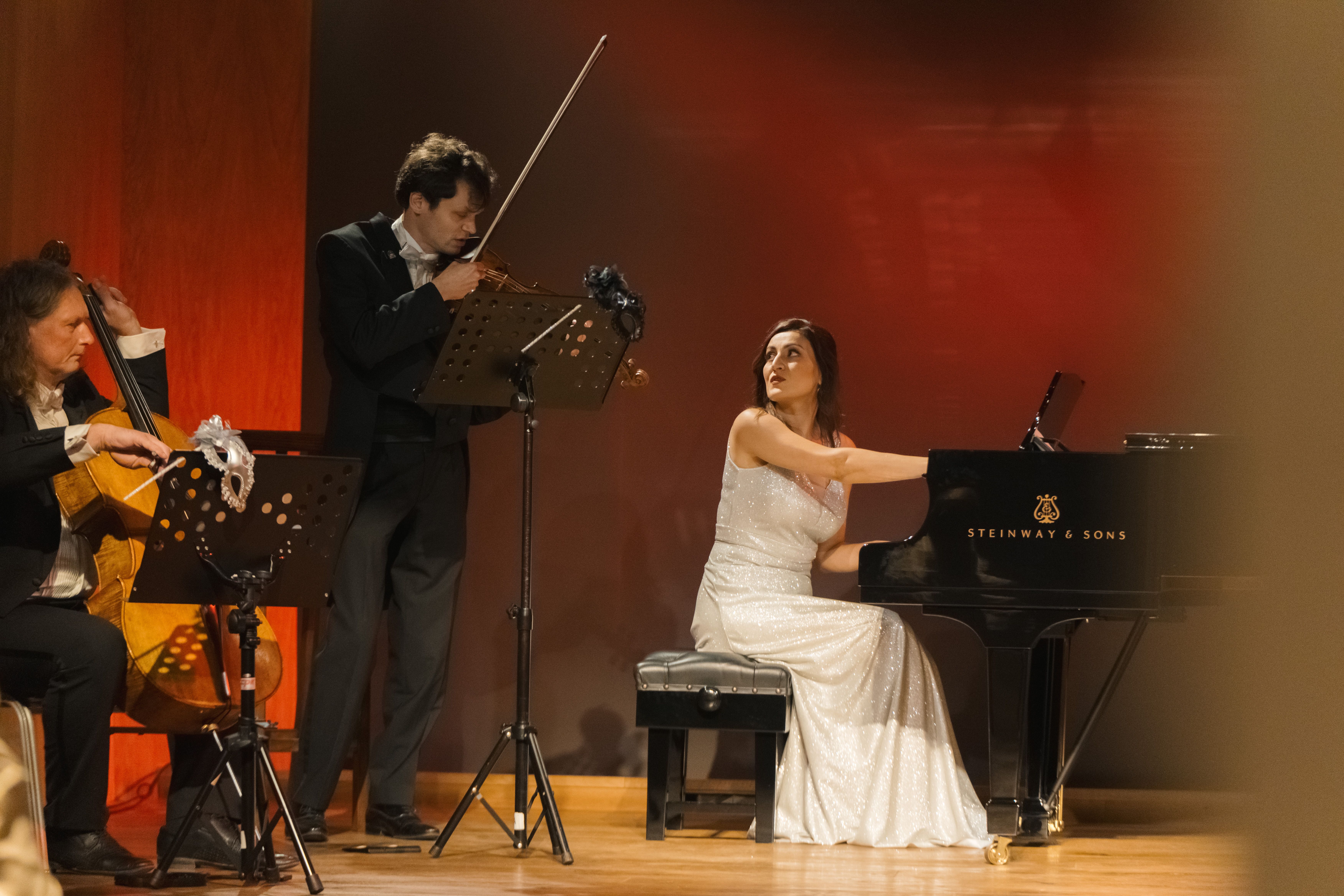 Female Pianist playing a Steinway piano with a violinist and cellist behind her