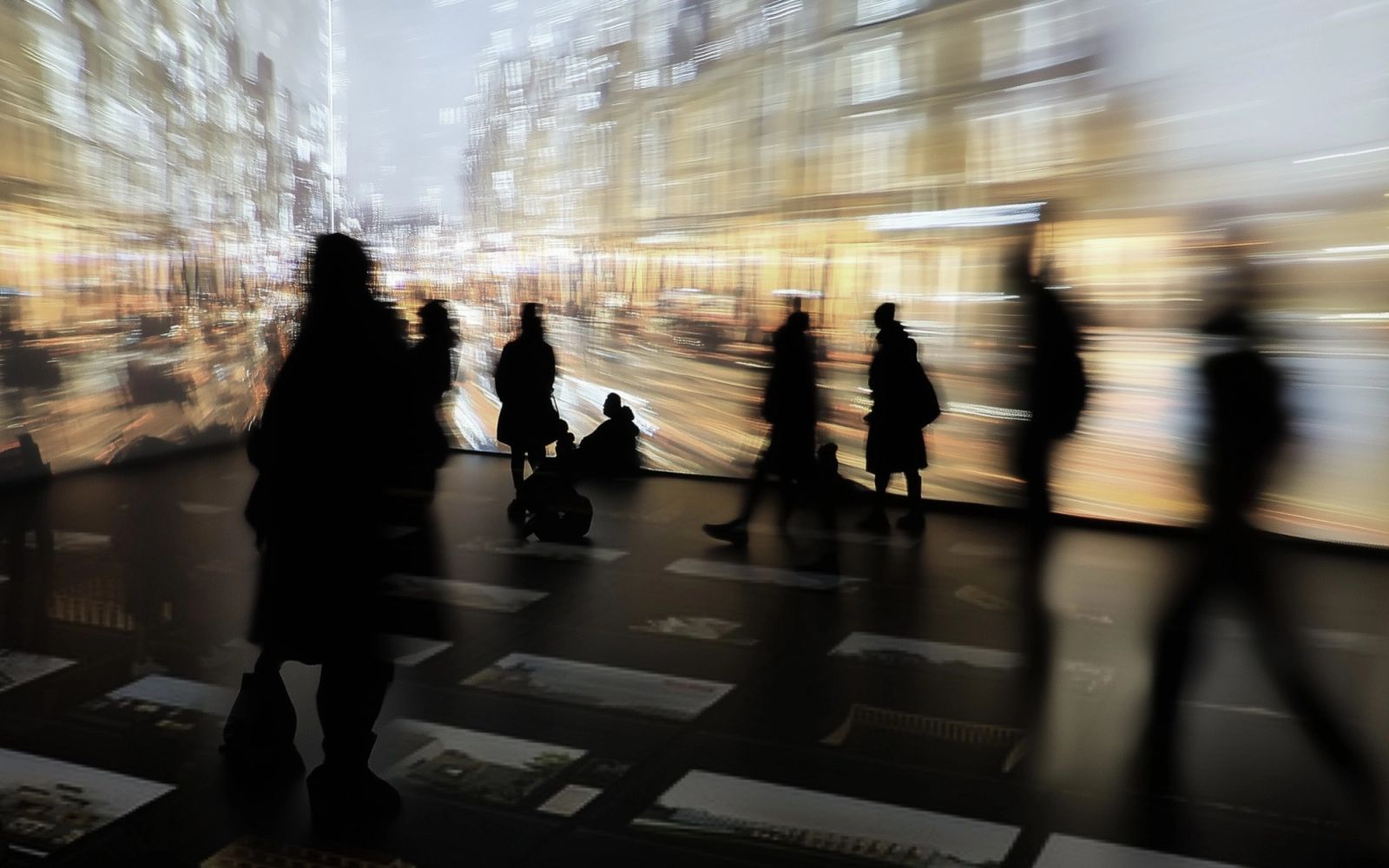 Visitors walking through an immersive room with projected city views