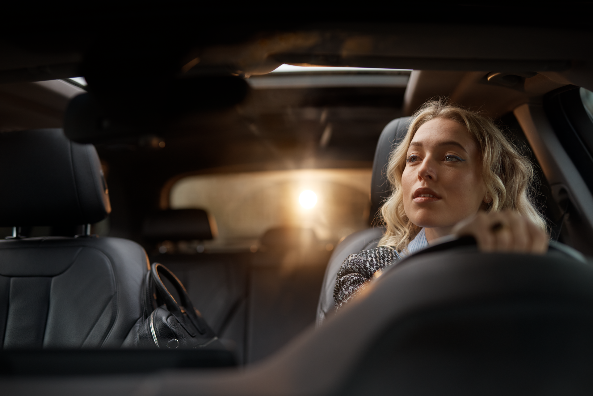 A woman in the driver's seat, looking in the rearview mirror.