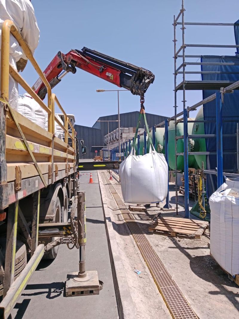 Grúa de camión trasladando insumos junto a andamios en faena de mantención de planta de filtrado