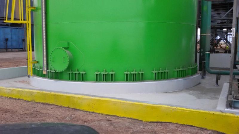 Estanque industrial revestido en verde, vista de la base con pernos de anclaje