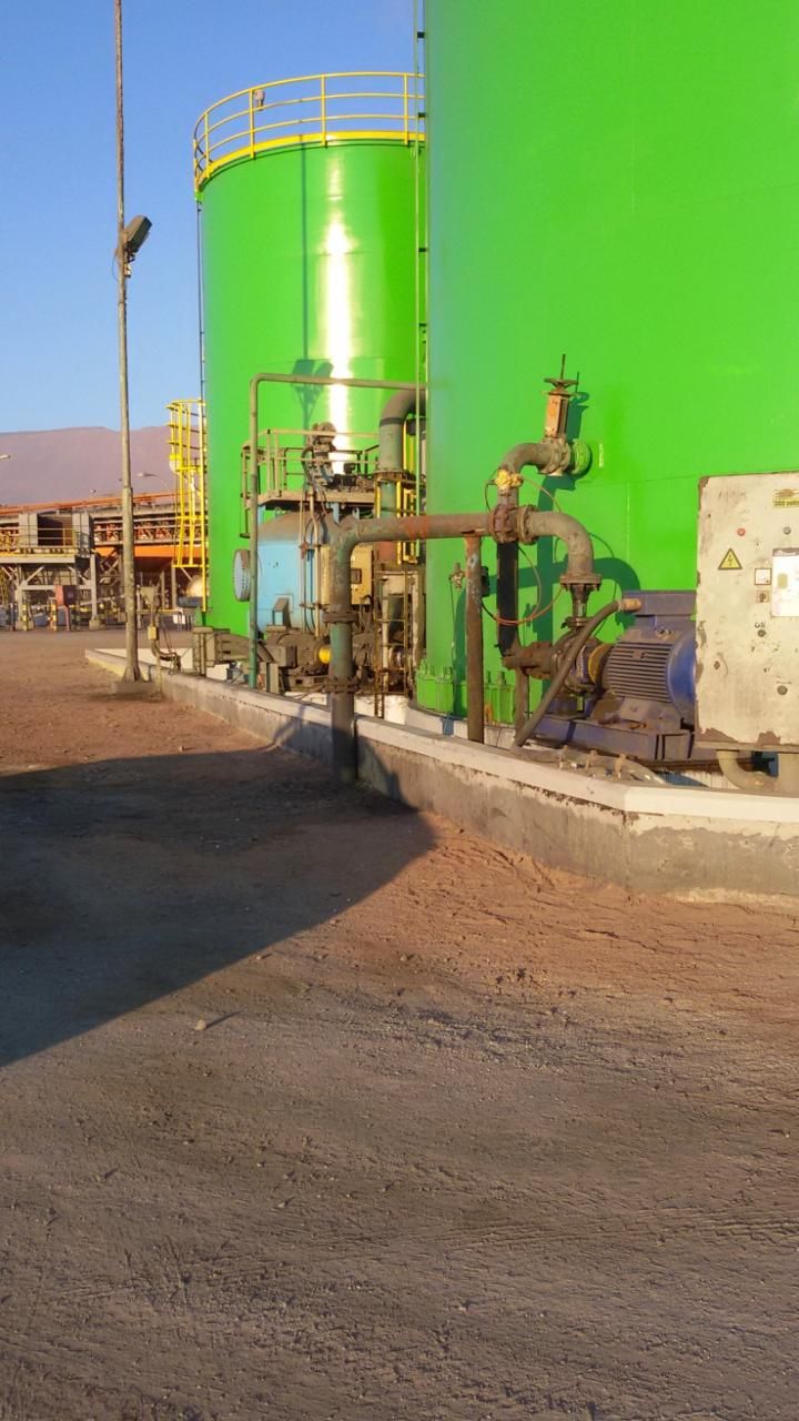 Estanques industriales revestidos en verde, con equipos de bombeo en primer plano