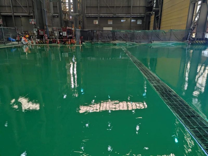Piso industrial con revestimiento epóxico verde y canaleta metálica