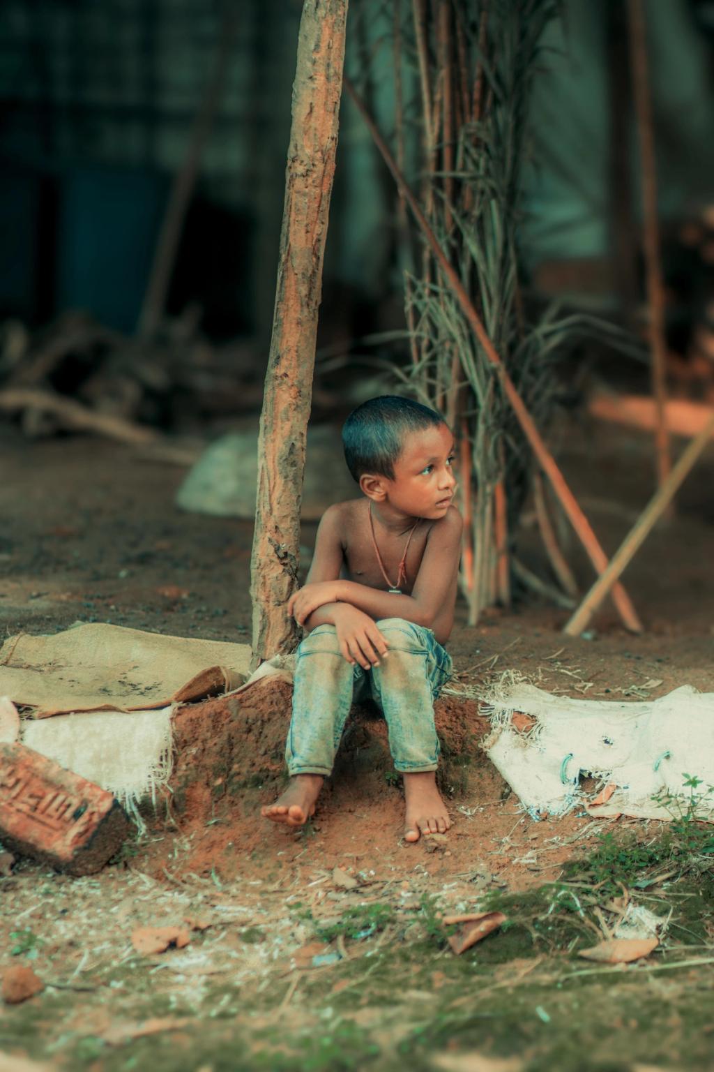 young child sat on house in village in Bangladesh