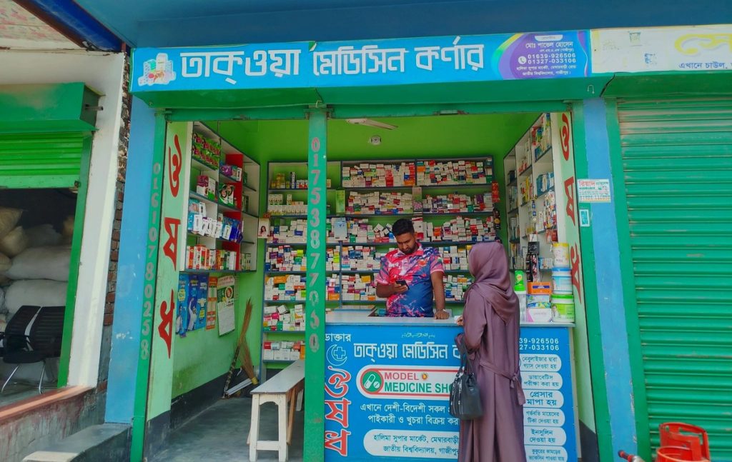 Man running pharmacy with female customer at desk