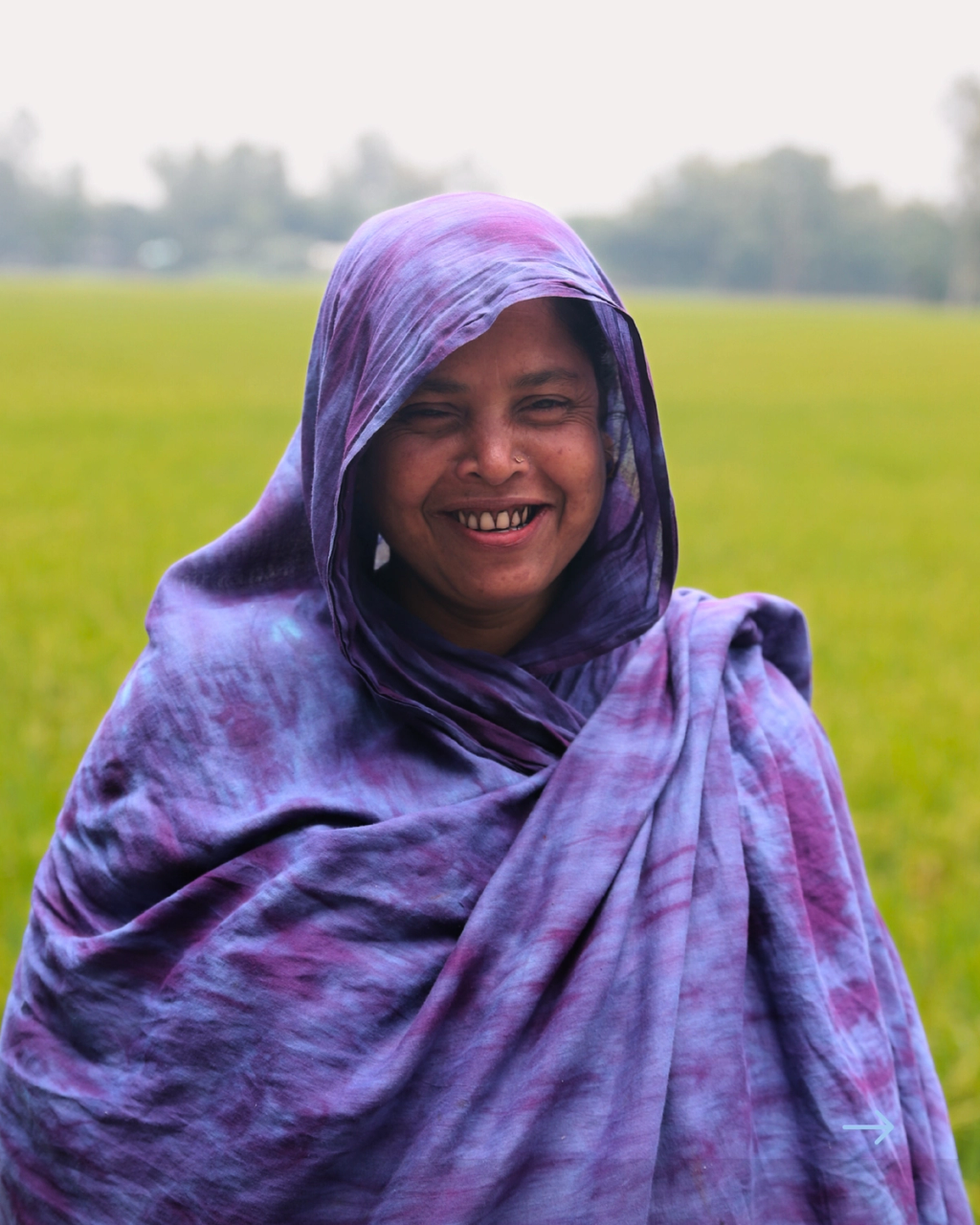 Farmer, Shanti Begum, smiling in front of her field.