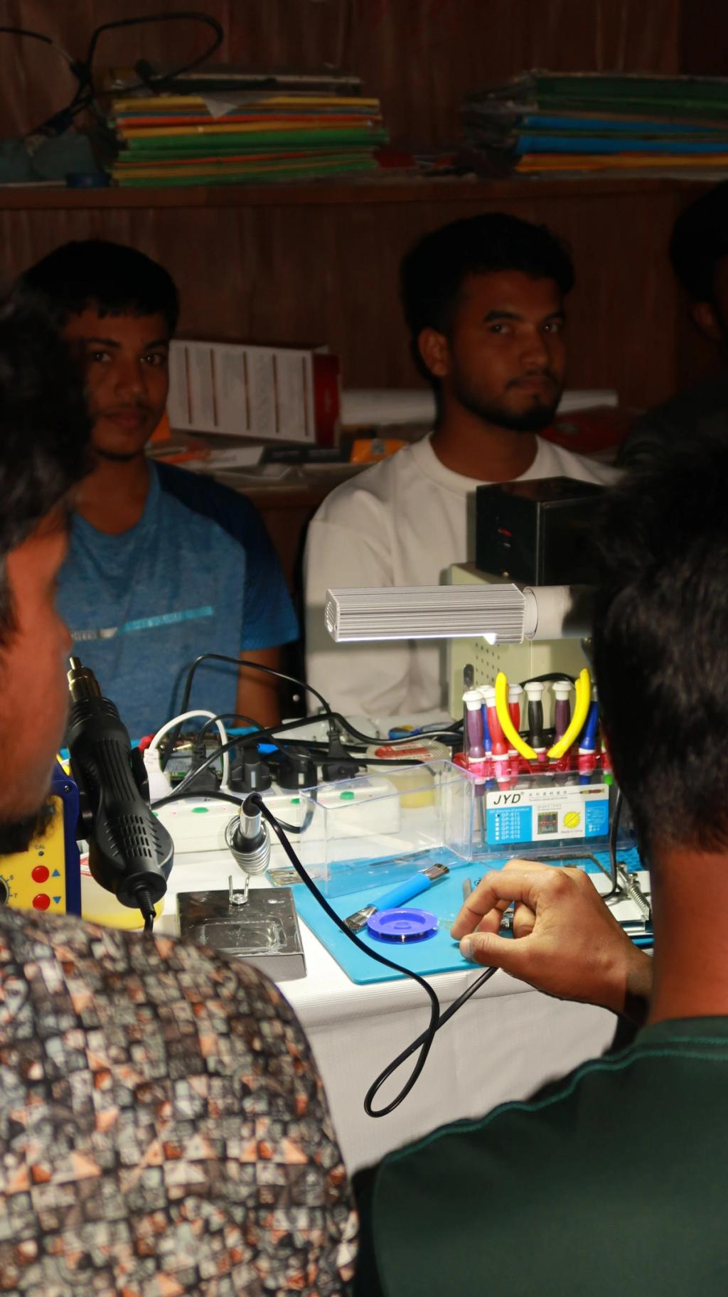 two men being trained repairing phones