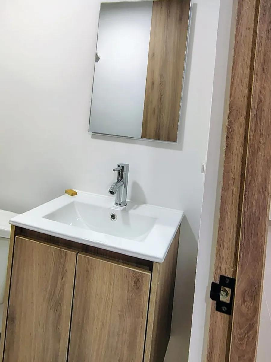 Mueble de lavamanos: Mueble flotante de dos puertas con espejo en la misma veta de madera.